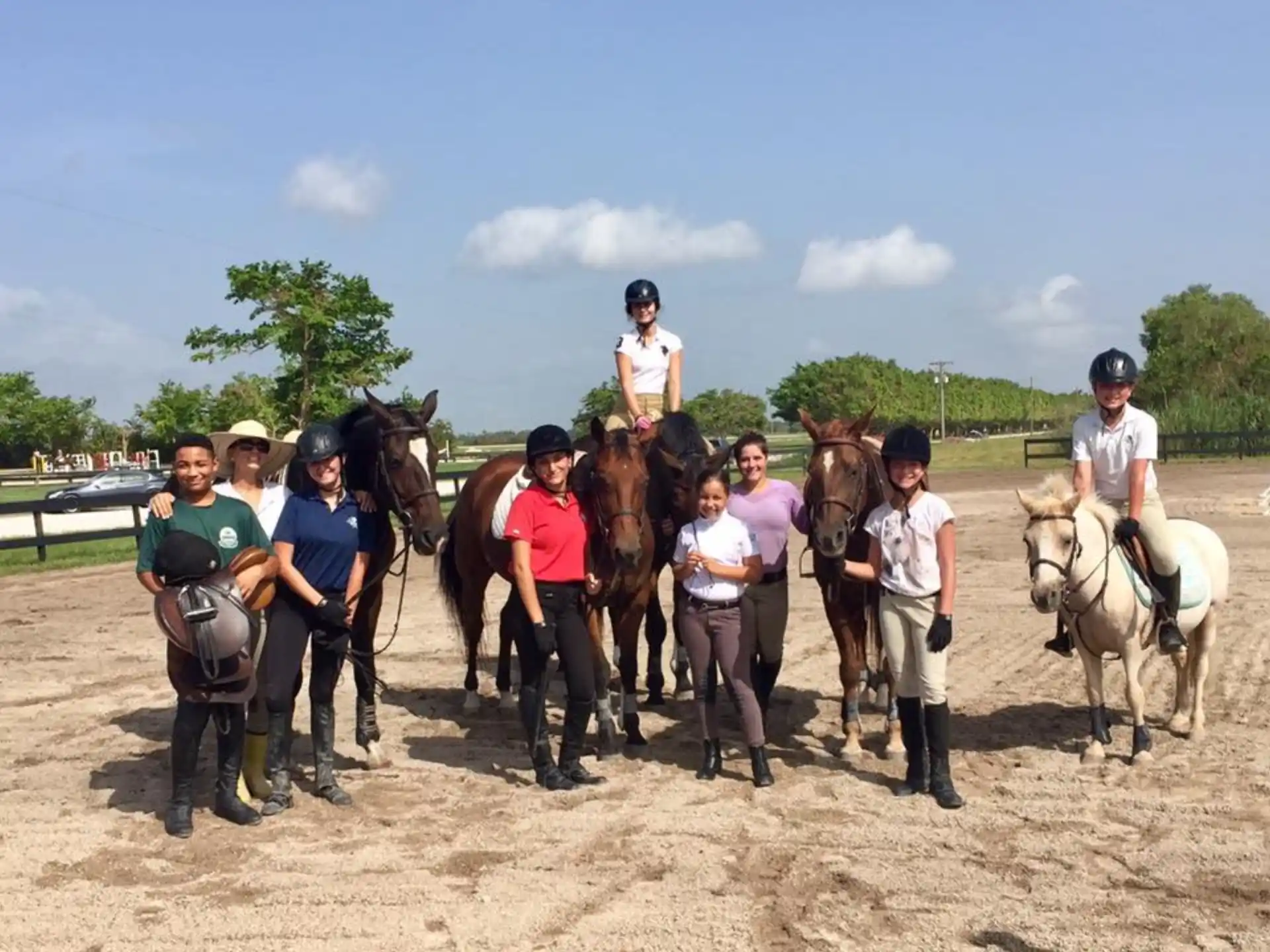 a group of people standing on a dirt road with horses