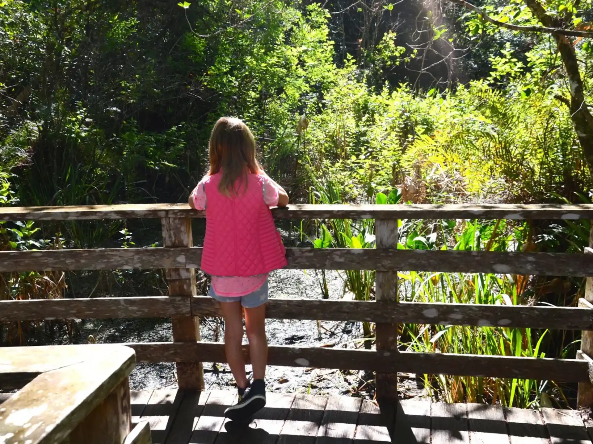 a girl standing on a wooden bridge