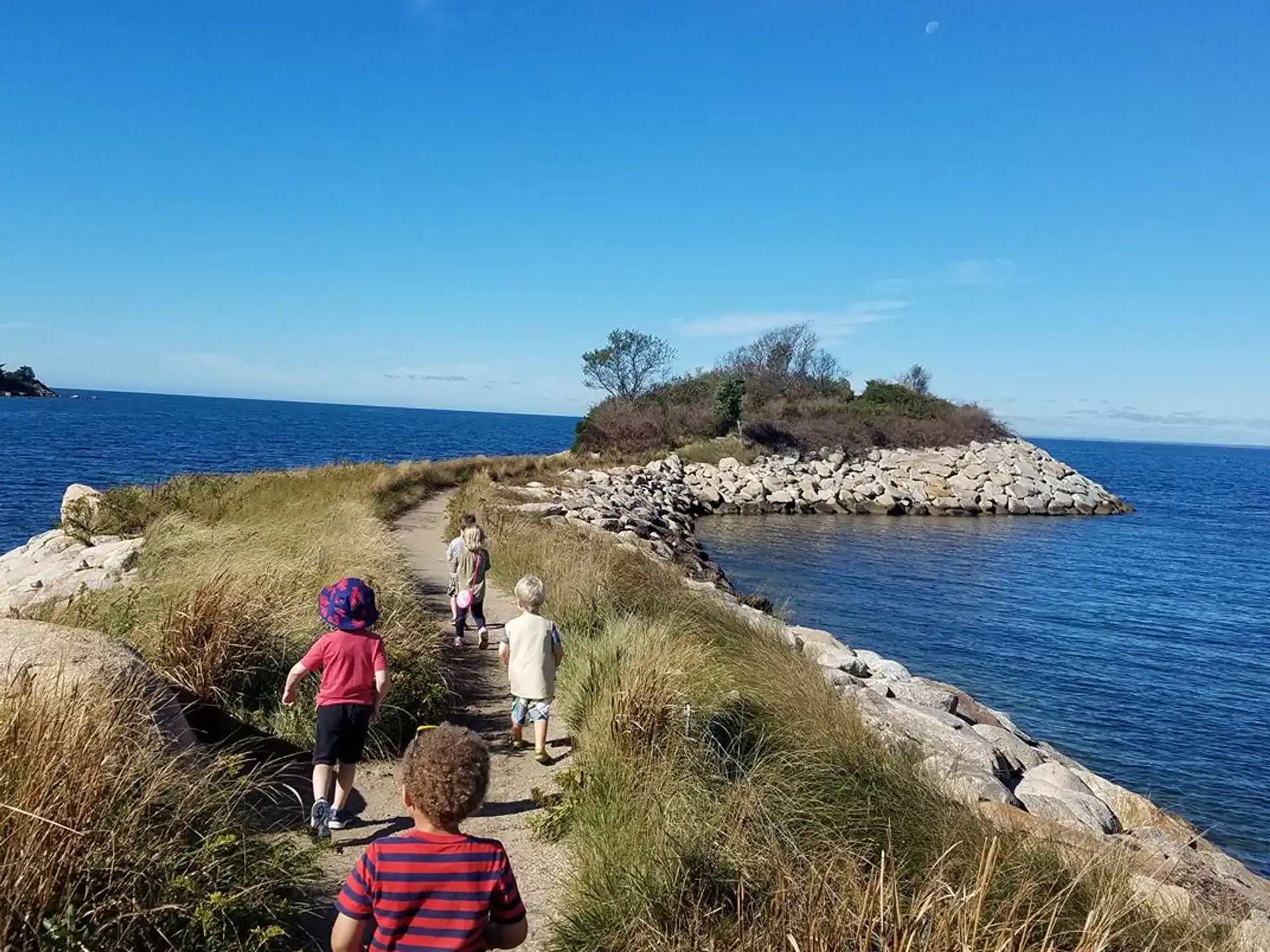 a group of people walking on a path by a body of water