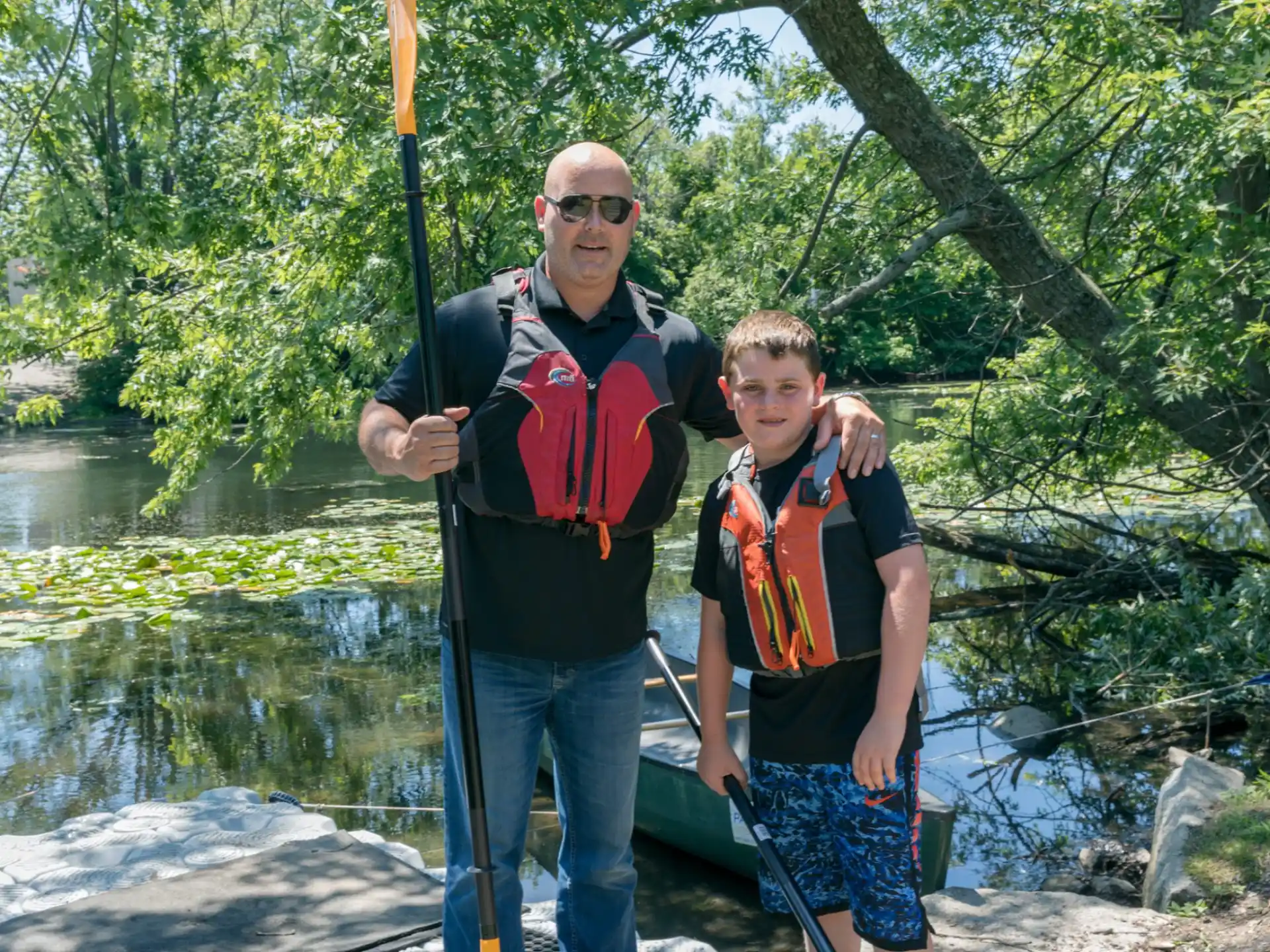a man and a boy posing for a picture next to a river
