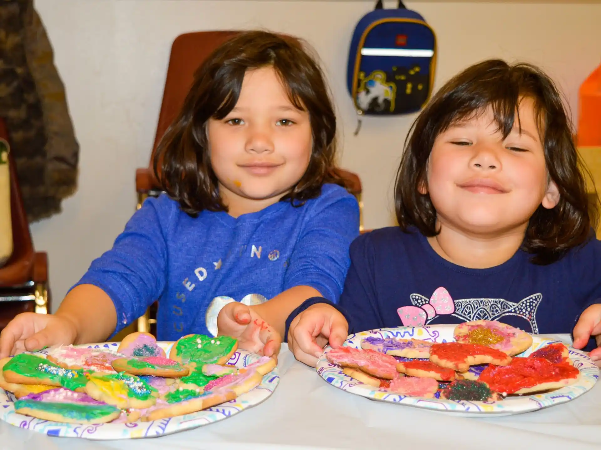 a couple of kids sit at a table with a plate of pizza