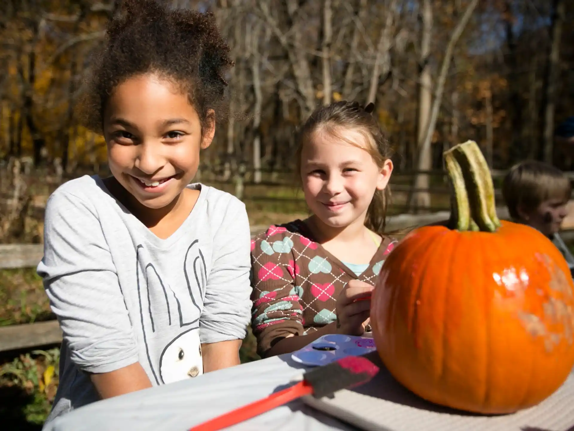 a couple of children sitting at a table with a pumpkin