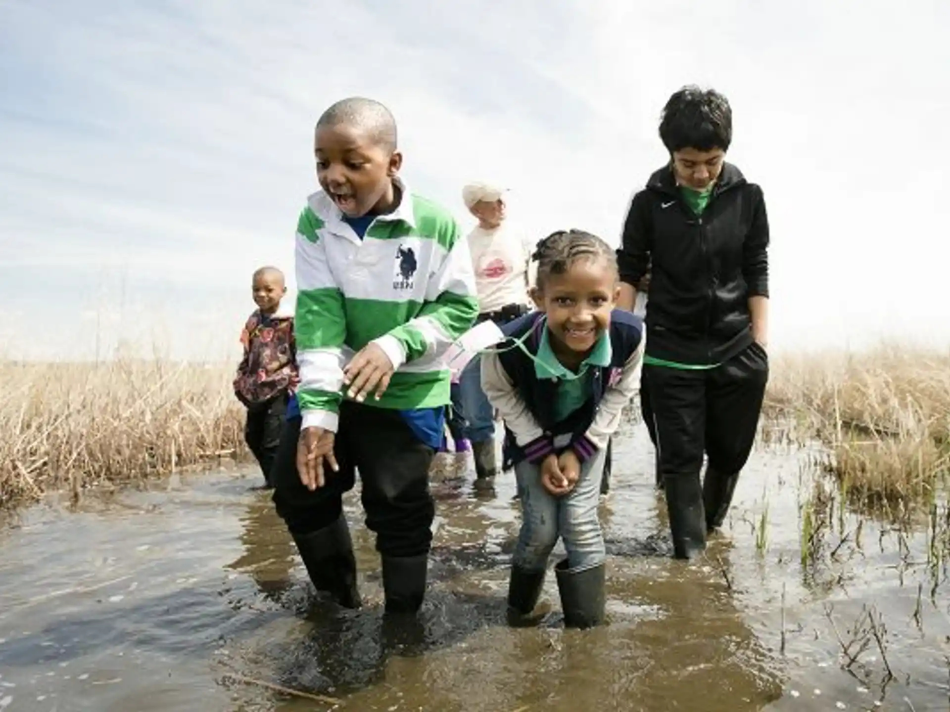 a group of people walking through a muddy puddle