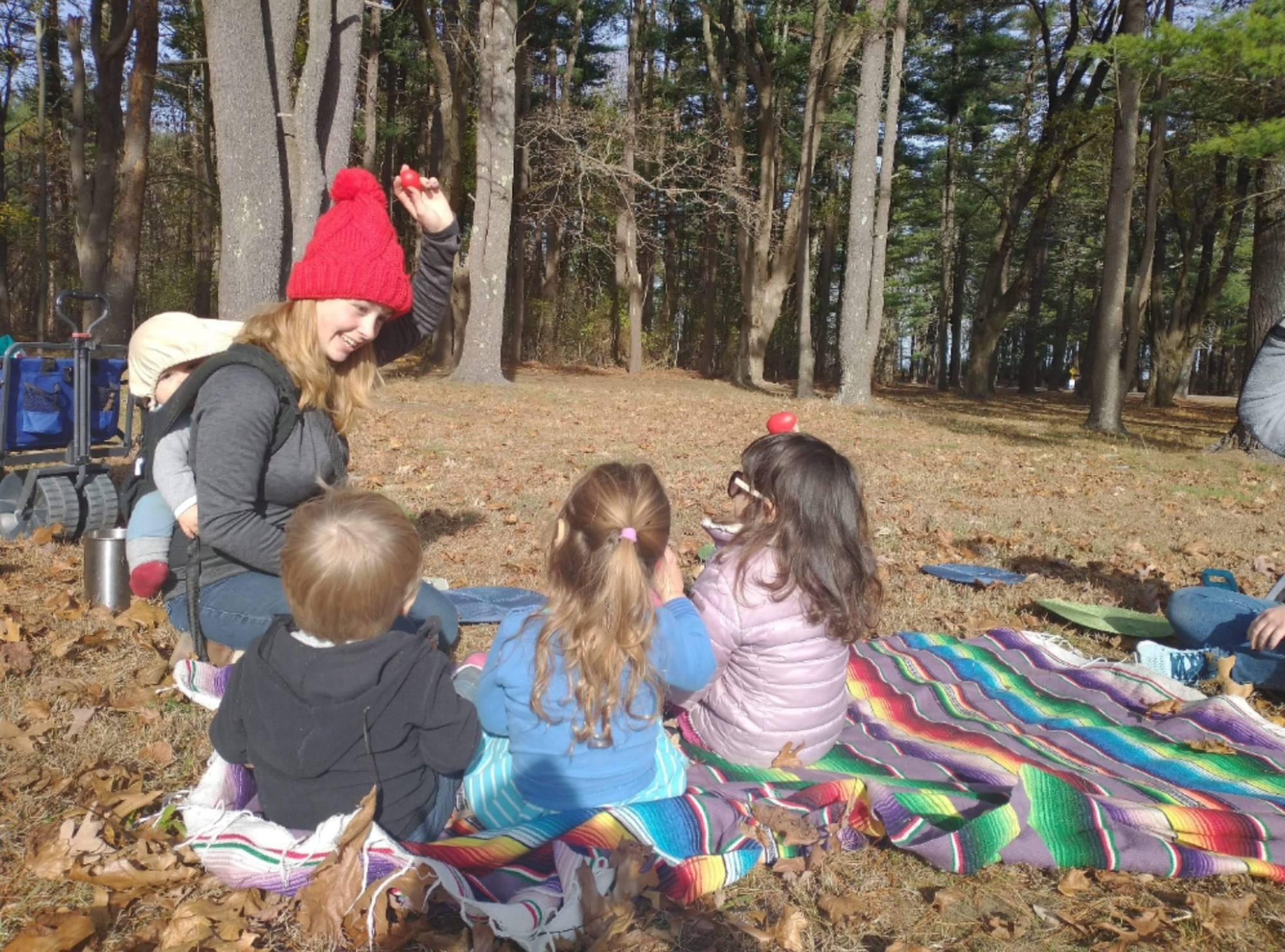 a group of people sitting on a blanket in a grassy area