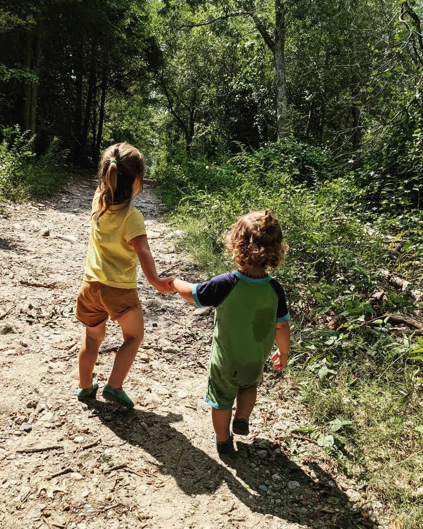 two children walking on a dirt path