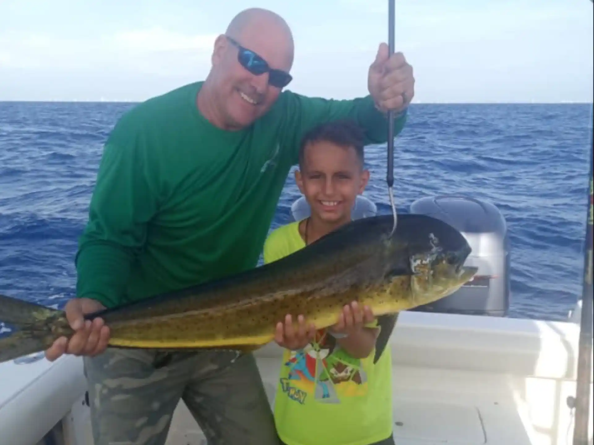 a man and a boy holding a fish on a boat