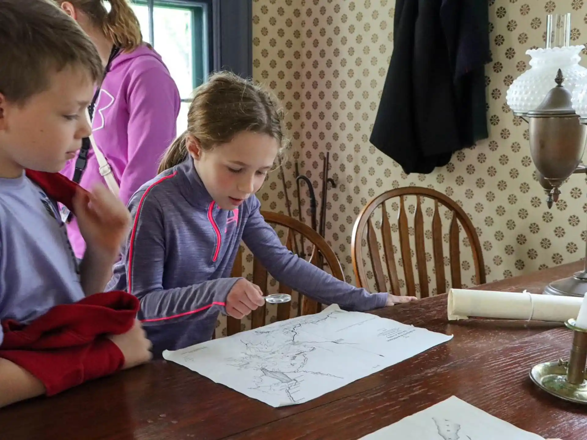 a group of children sitting at a table looking at a piece of paper
