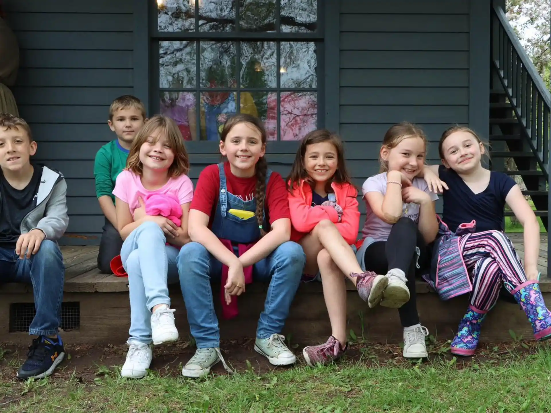 a group of children sitting on a bench outside a house