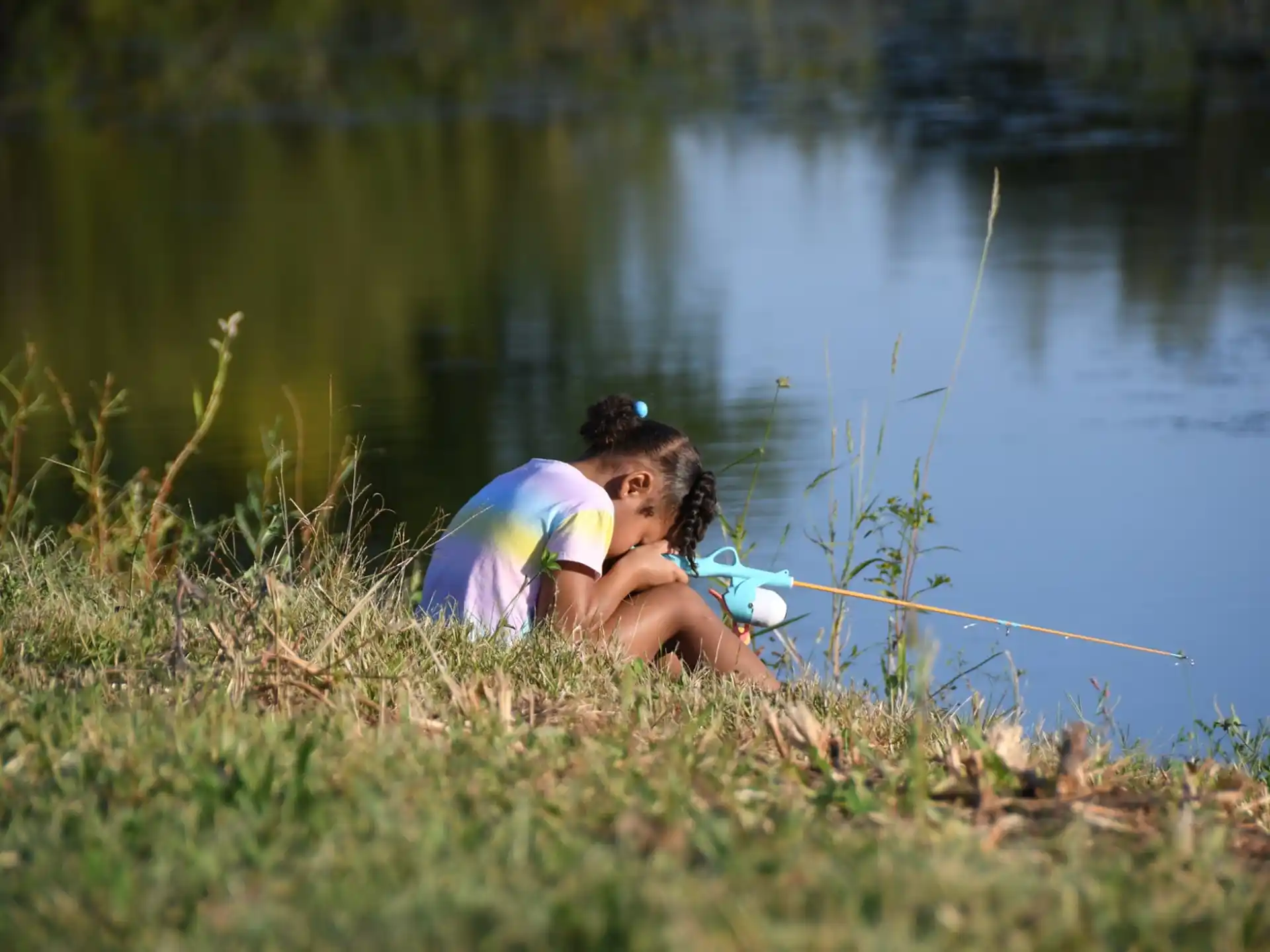a person lying in the grass next to a body of water