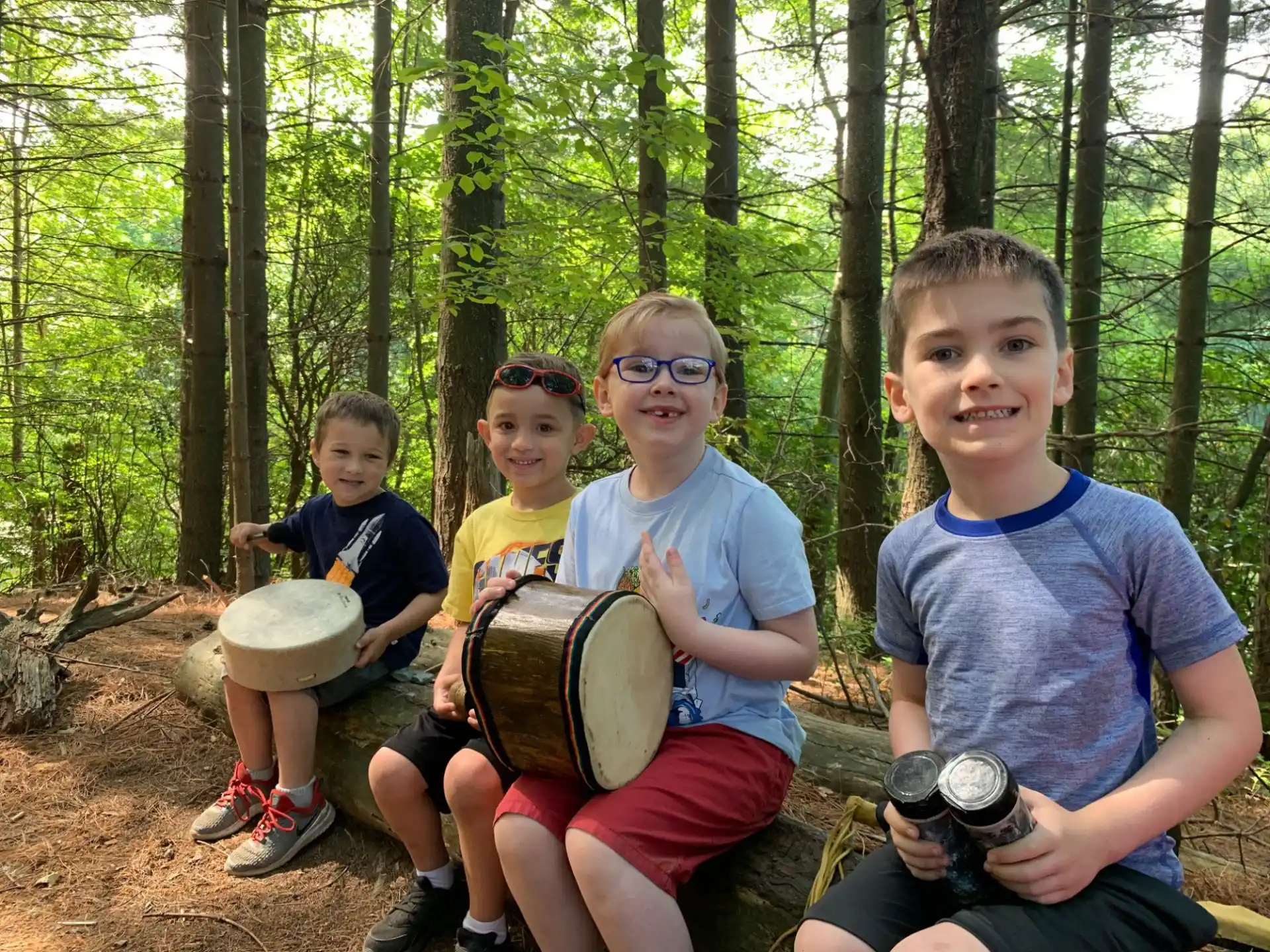 a group of kids holding drums in the woods