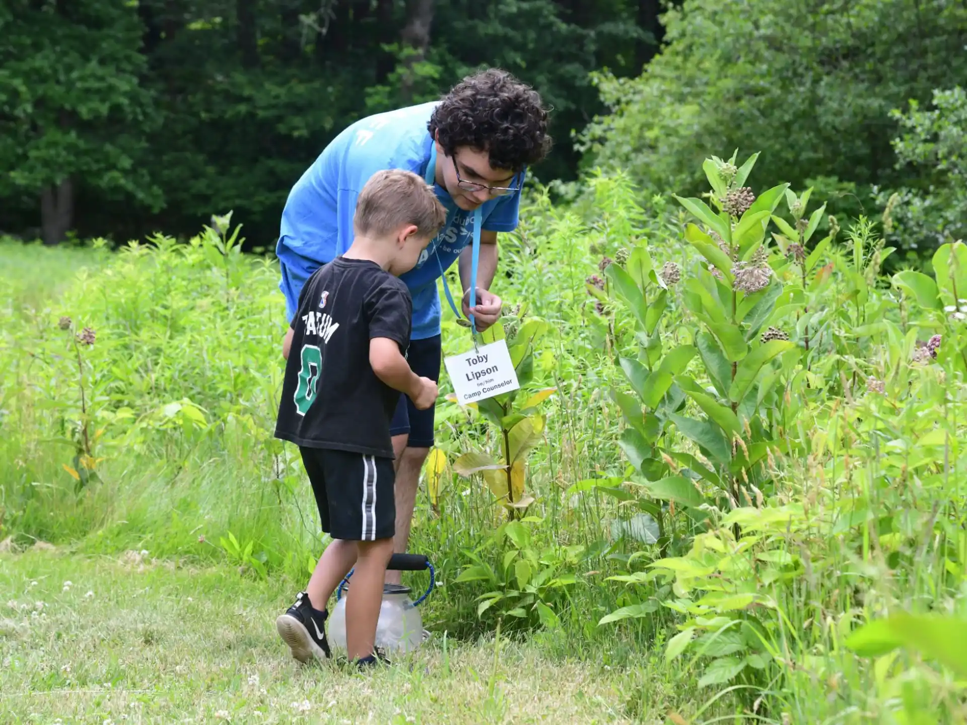 a man and a boy looking at a bag in a garden