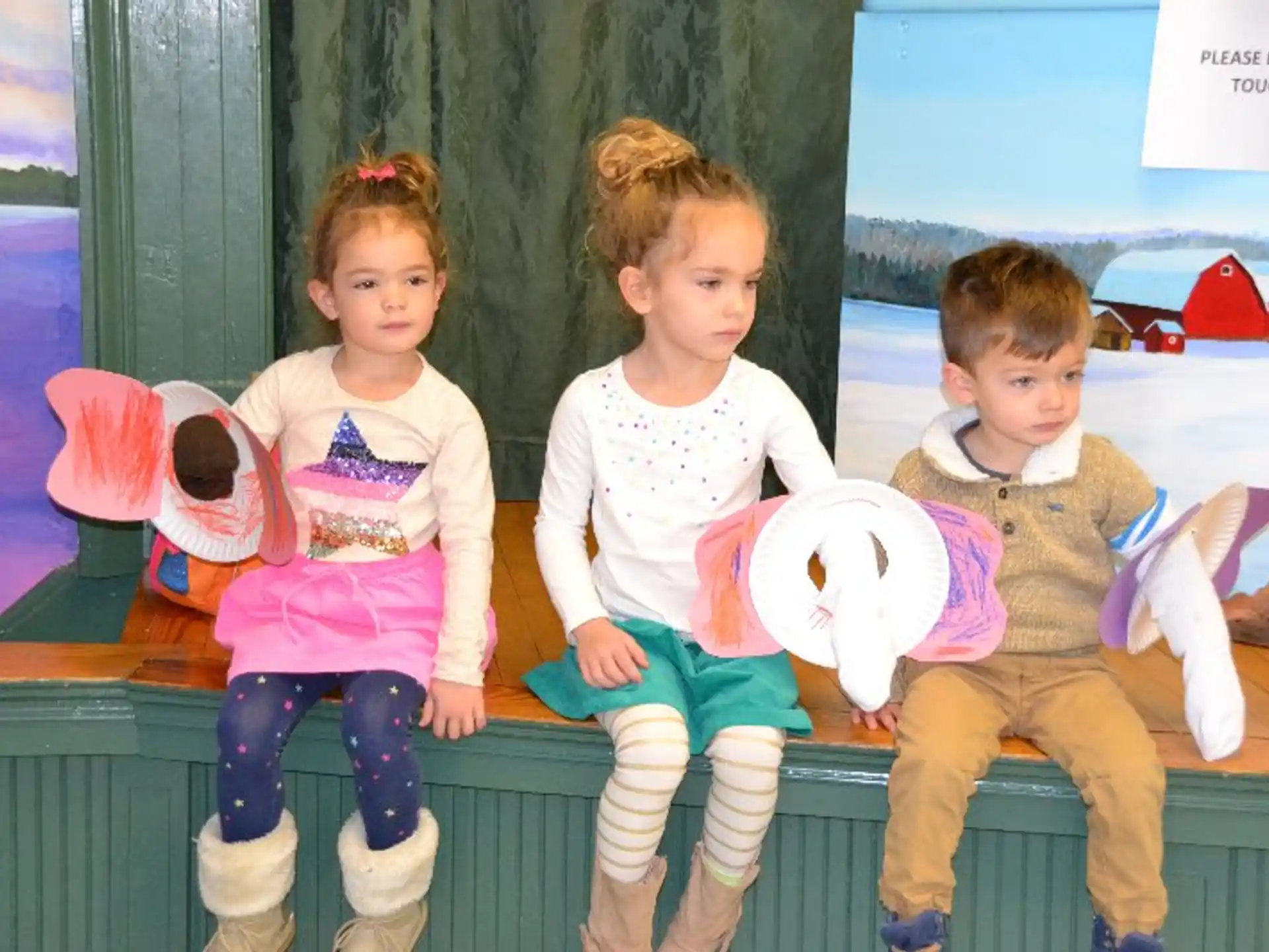 a group of children sitting on a bench with stuffed animals