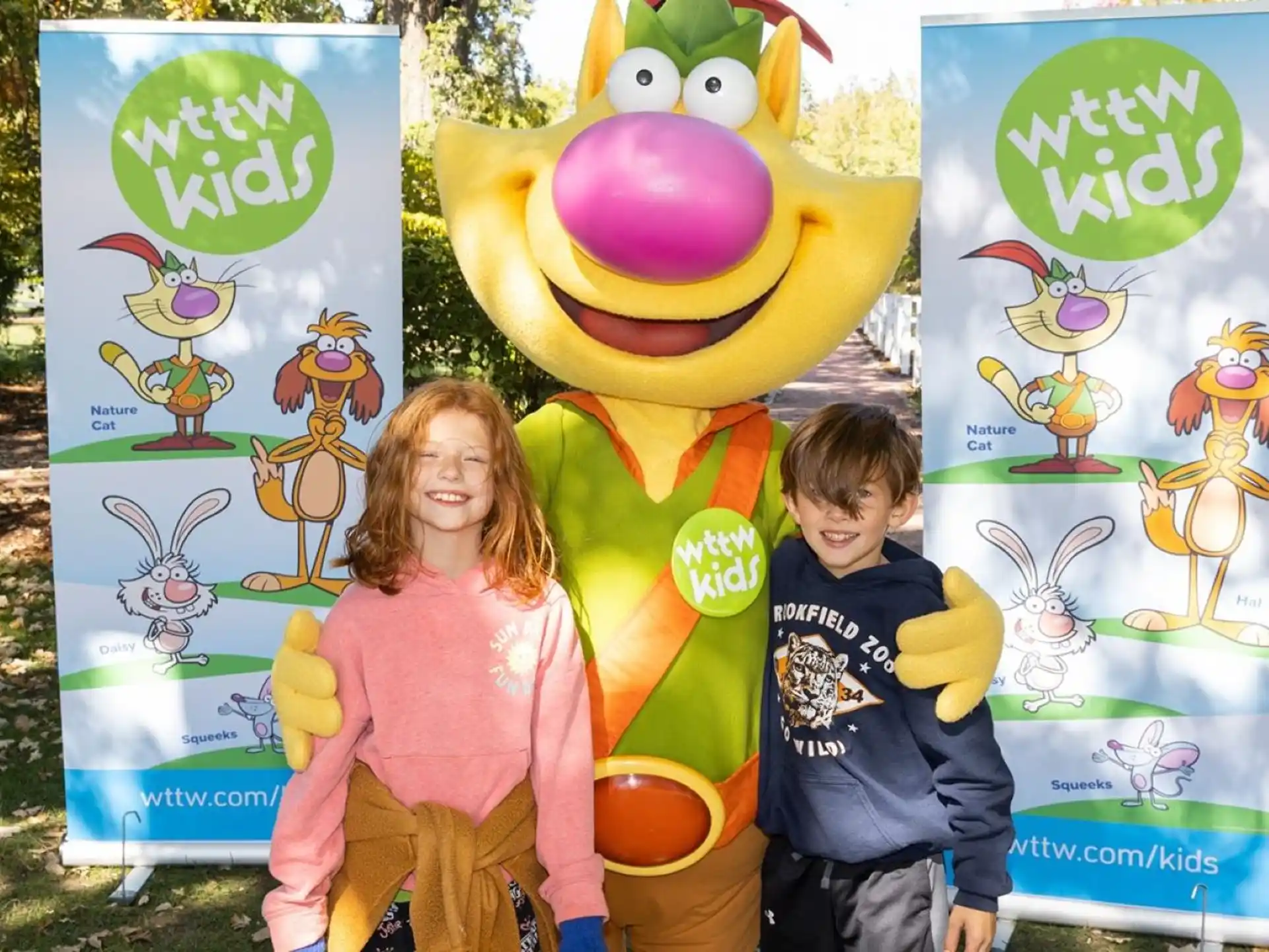 a boy and girl posing with a large cartoon character