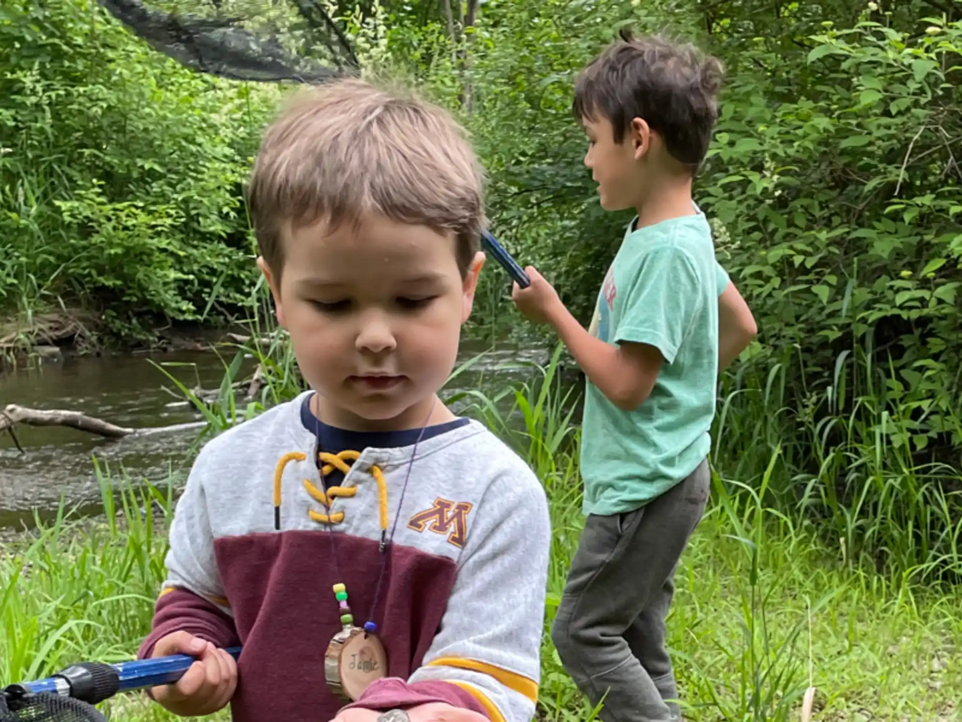 a couple of boys standing by a river with a bicycle