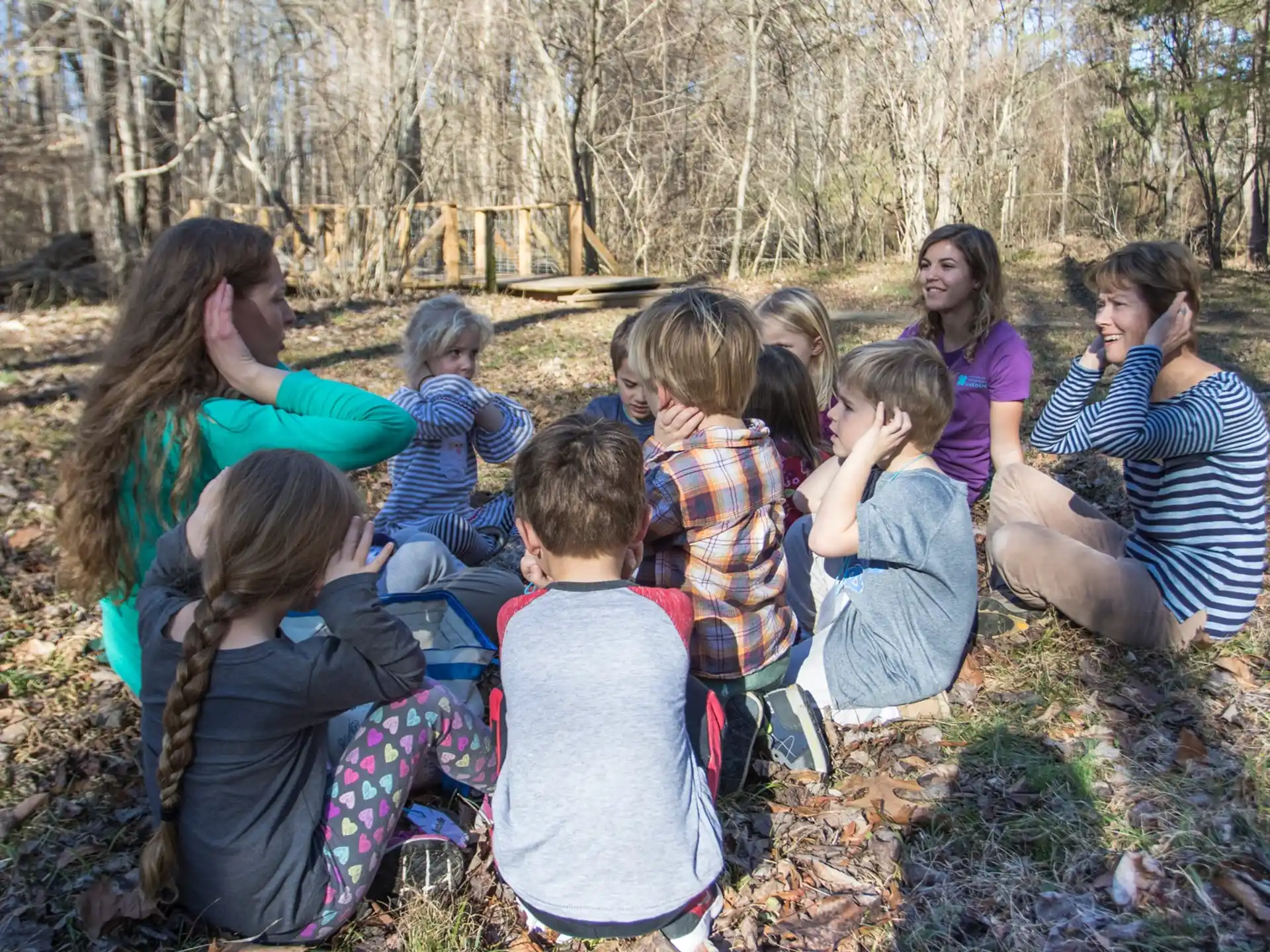 a group of children sitting in a circle in the woods