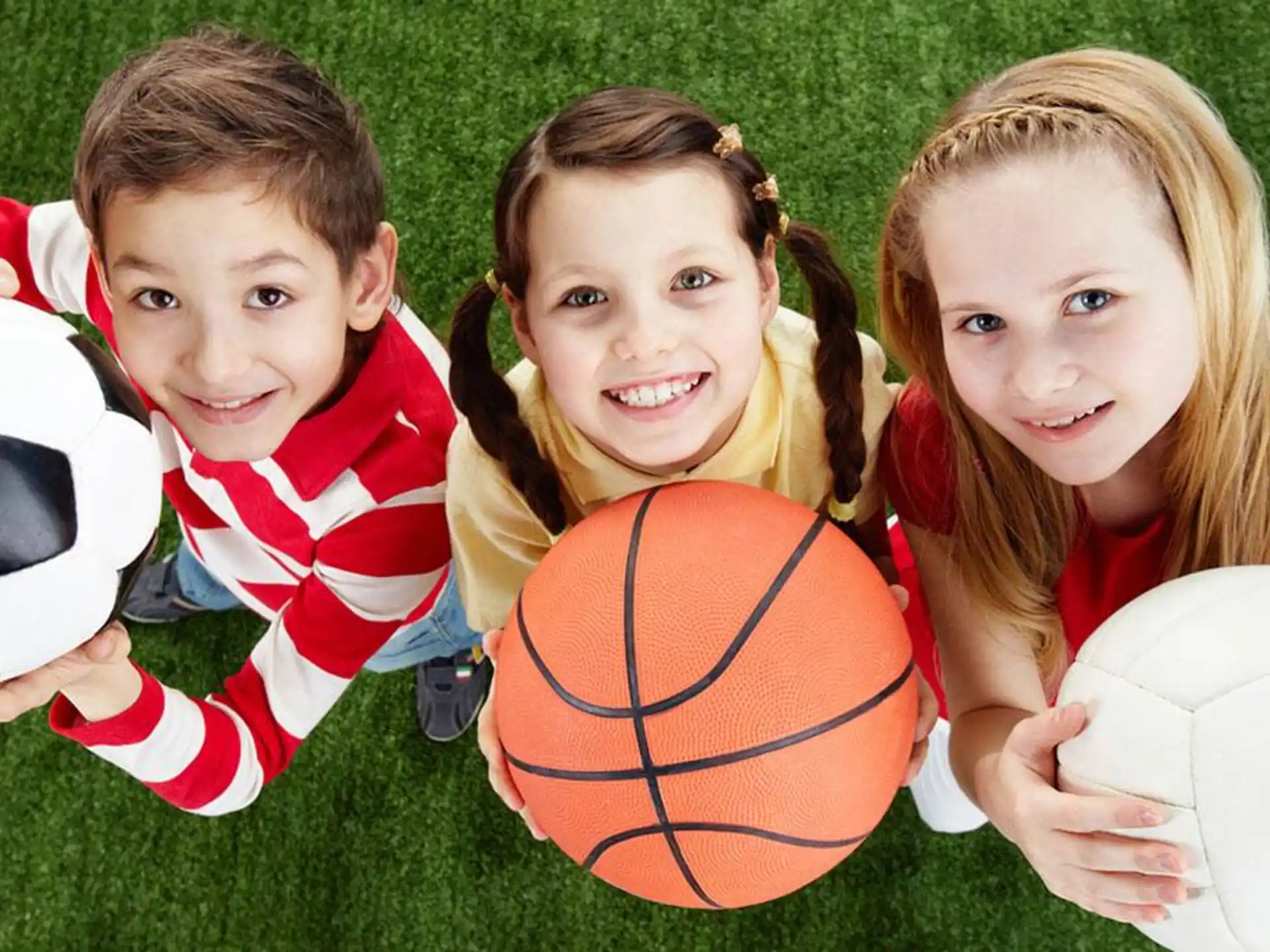 a group of children holding football balls