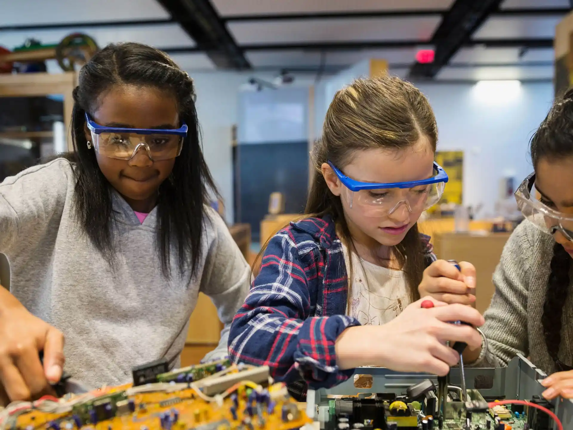 a group of people wearing safety goggles and looking at a circuit board