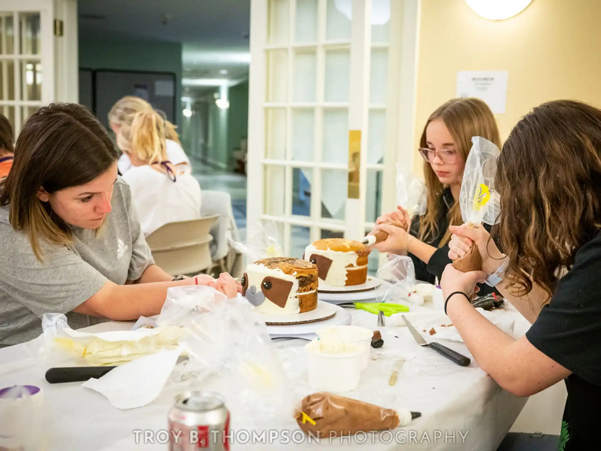 a group of people gather around a table with cakes