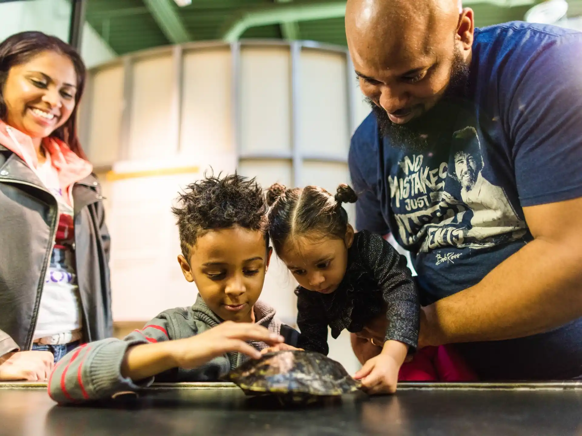 a man and woman with children playing with a turtle