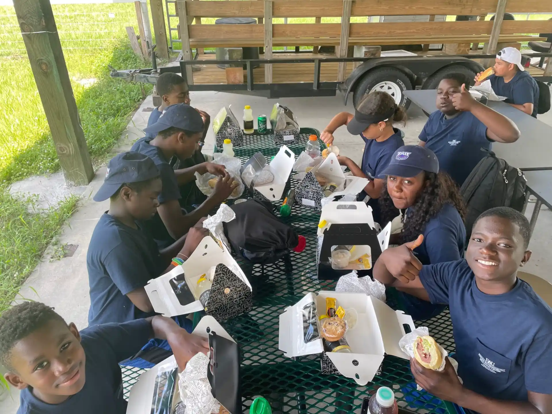 a group of people sitting at a picnic table eating food