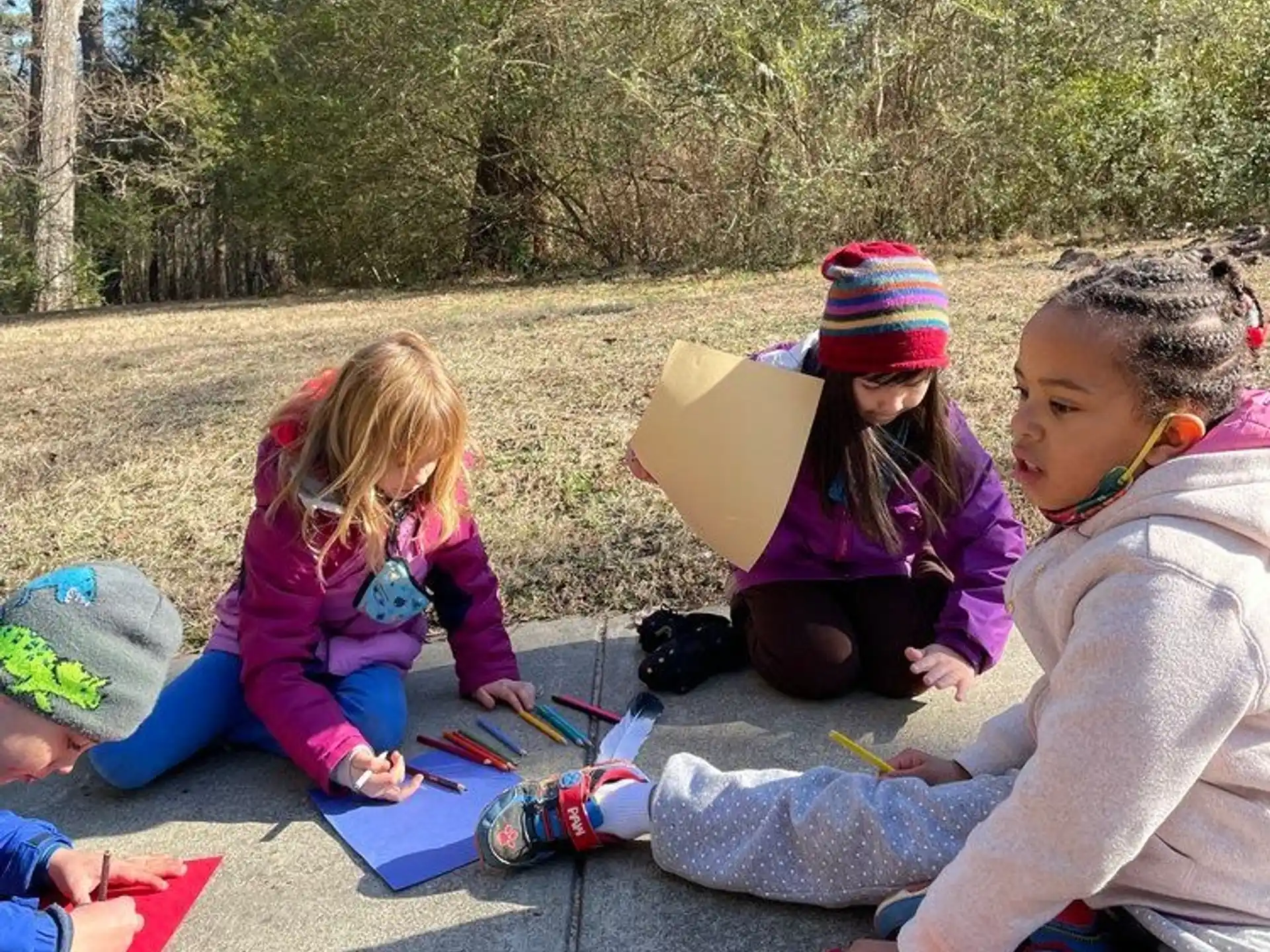 a group of children sitting on the ground outside