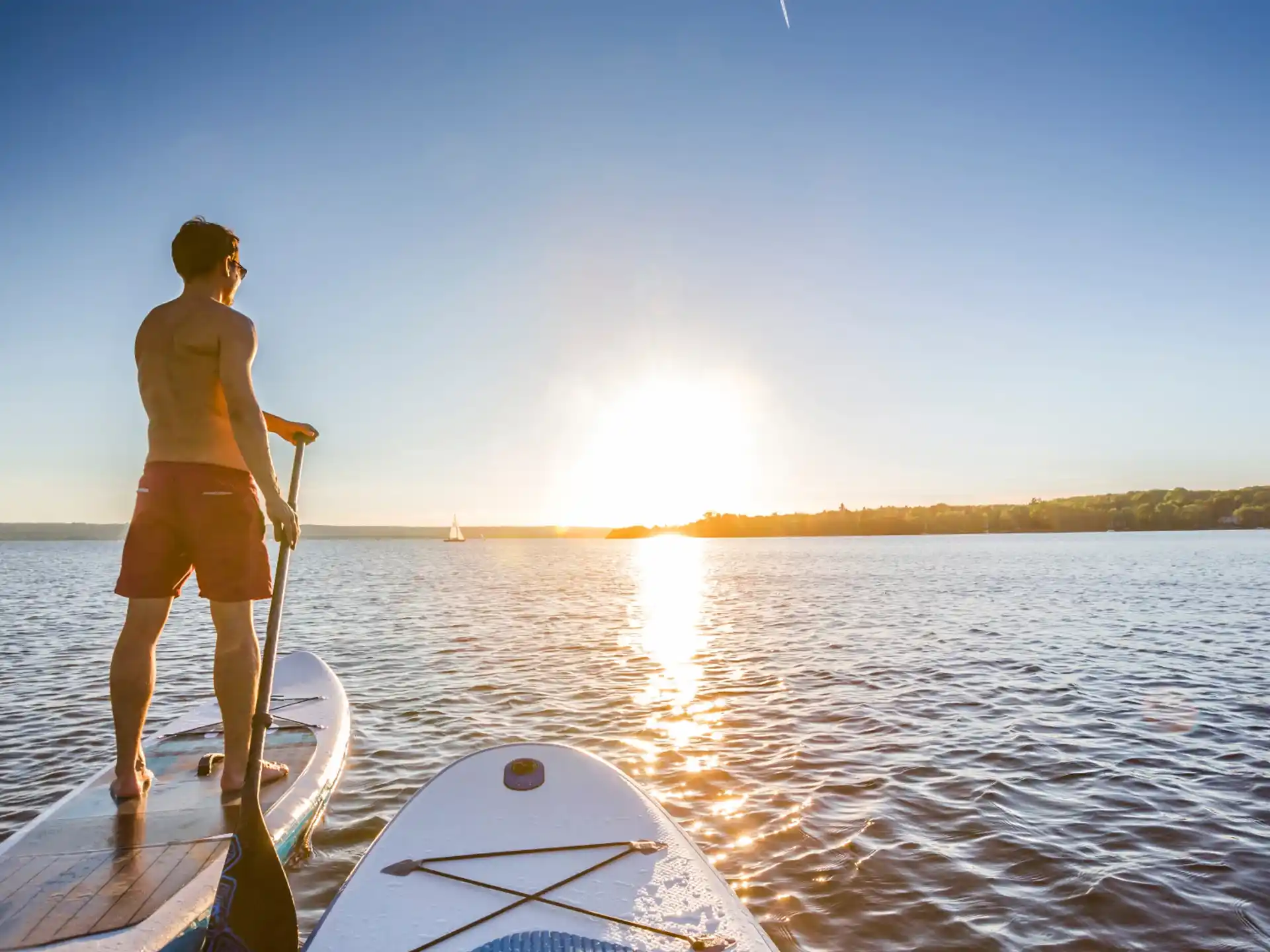 a man on a boat in the water with the sun setting