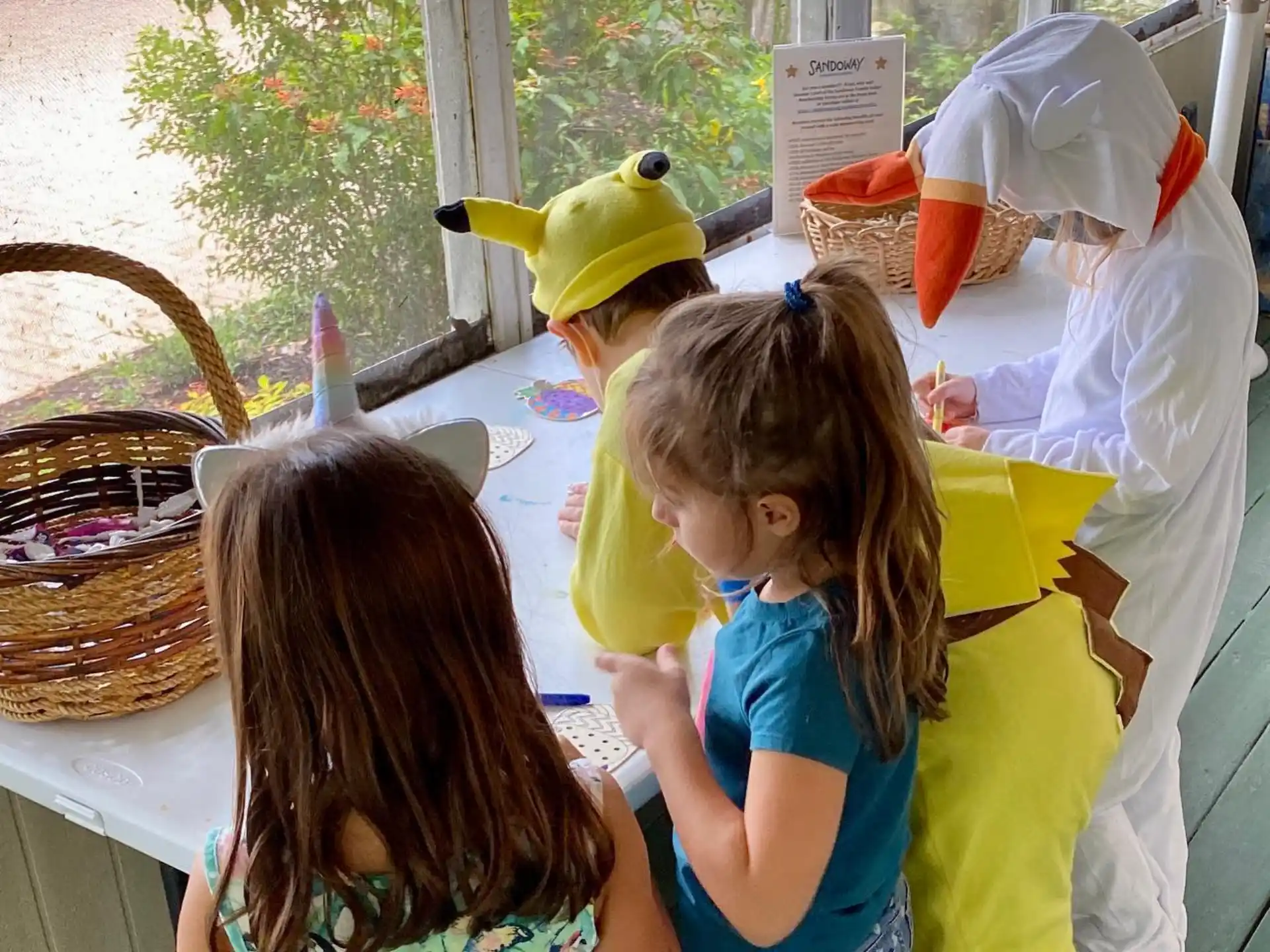 a couple of girls sitting at a table with a yellow stuffed animal