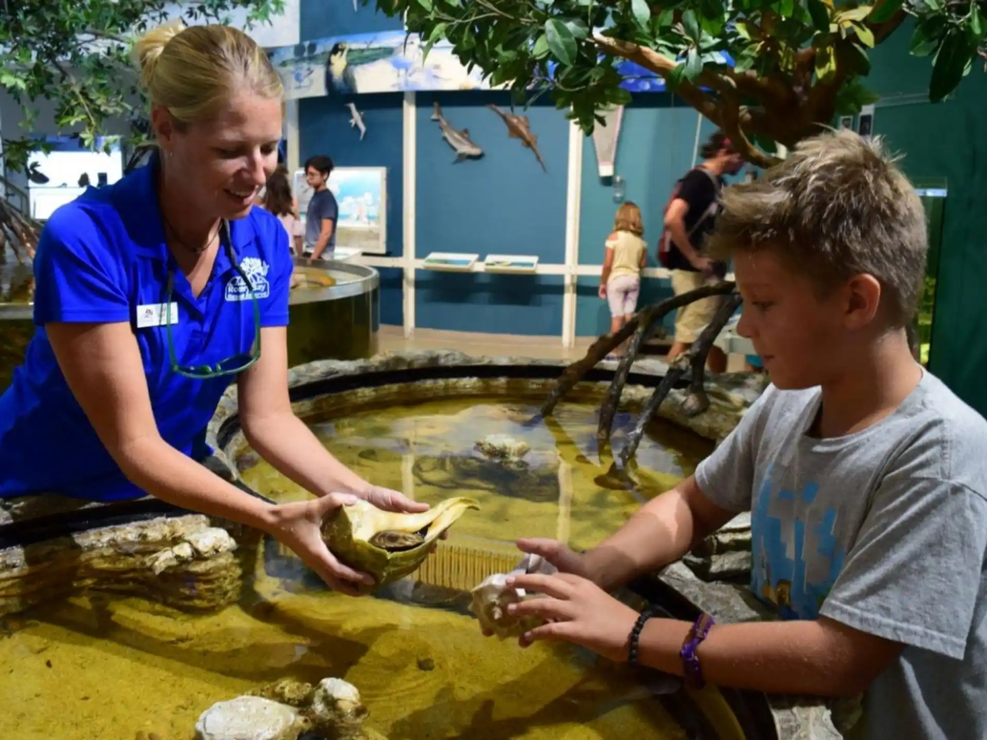 a person and a boy looking at a fish in a pond