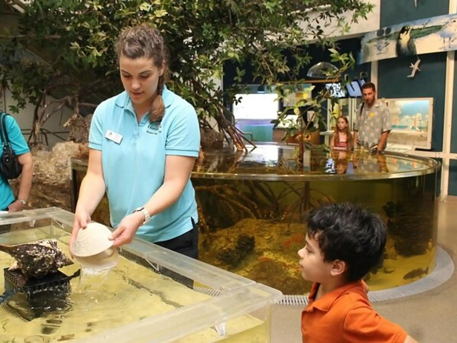a person and a boy standing by a table with a fish
