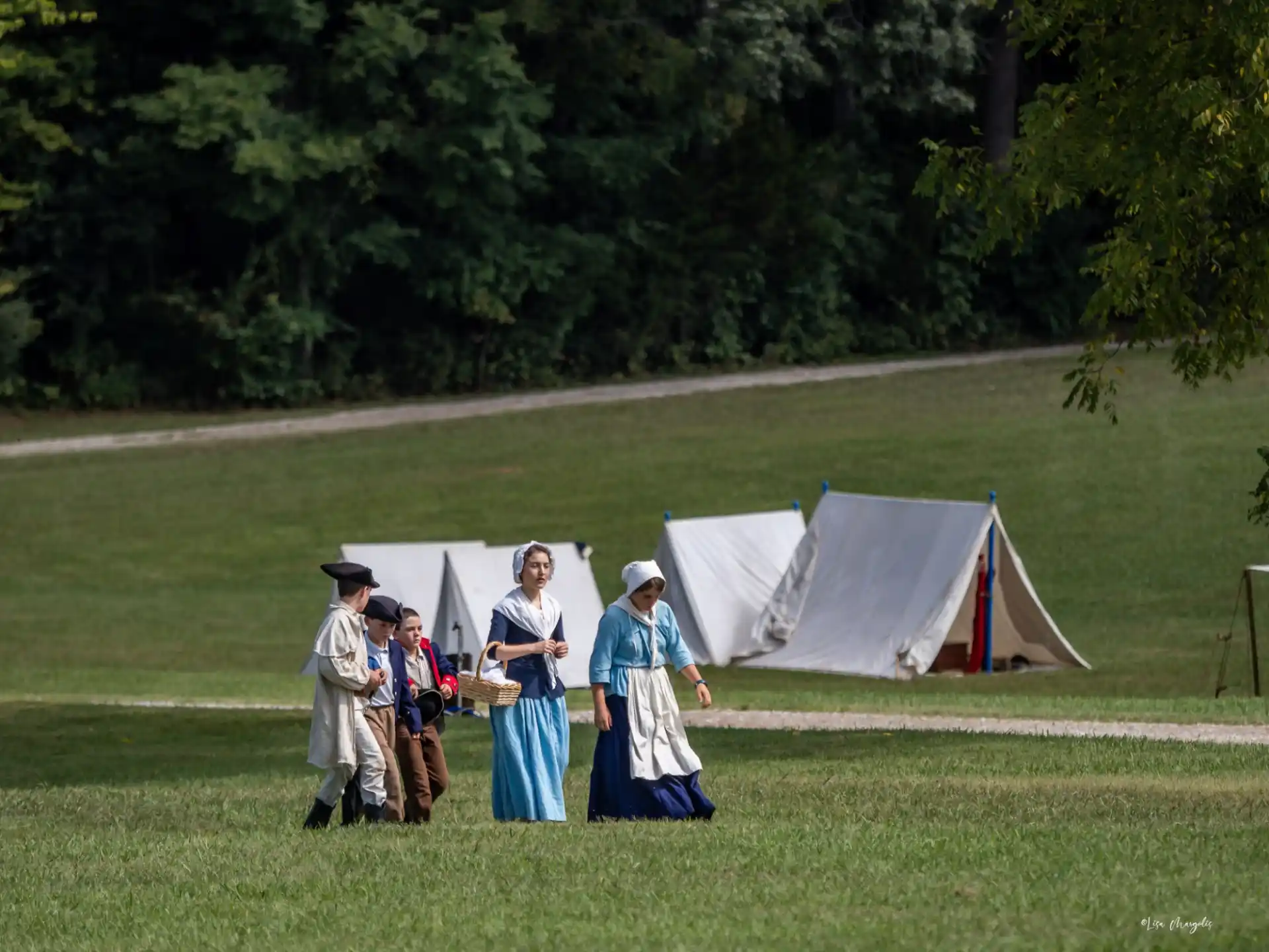 a group of people in clothing standing in front of a tent