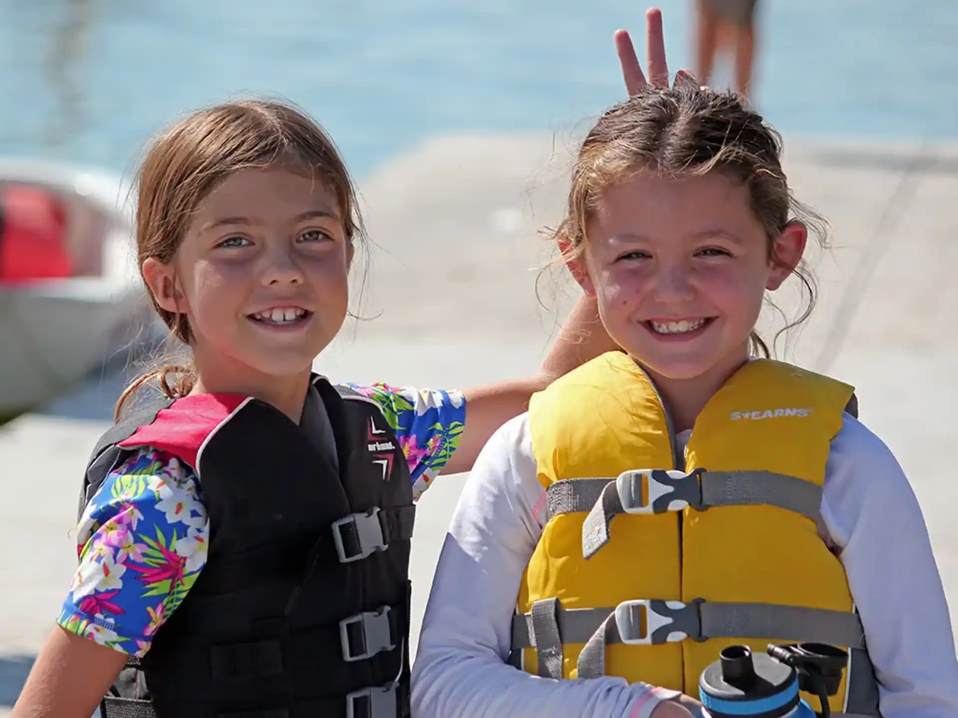 a couple of girls wearing life jackets and smiling at the camera
