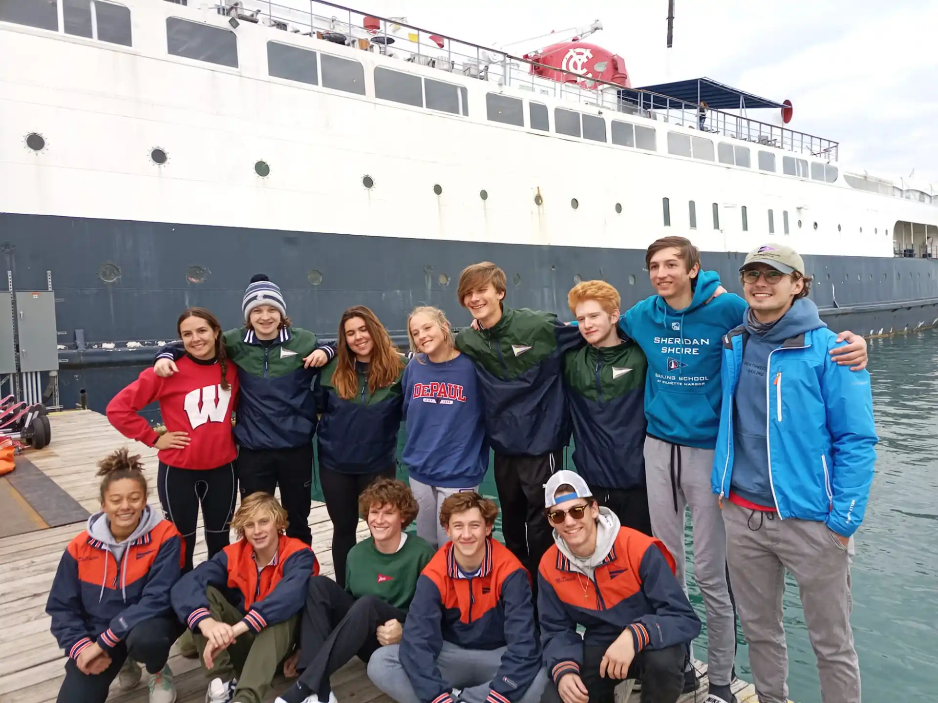 a group of people posing for a photo in front of a large ship