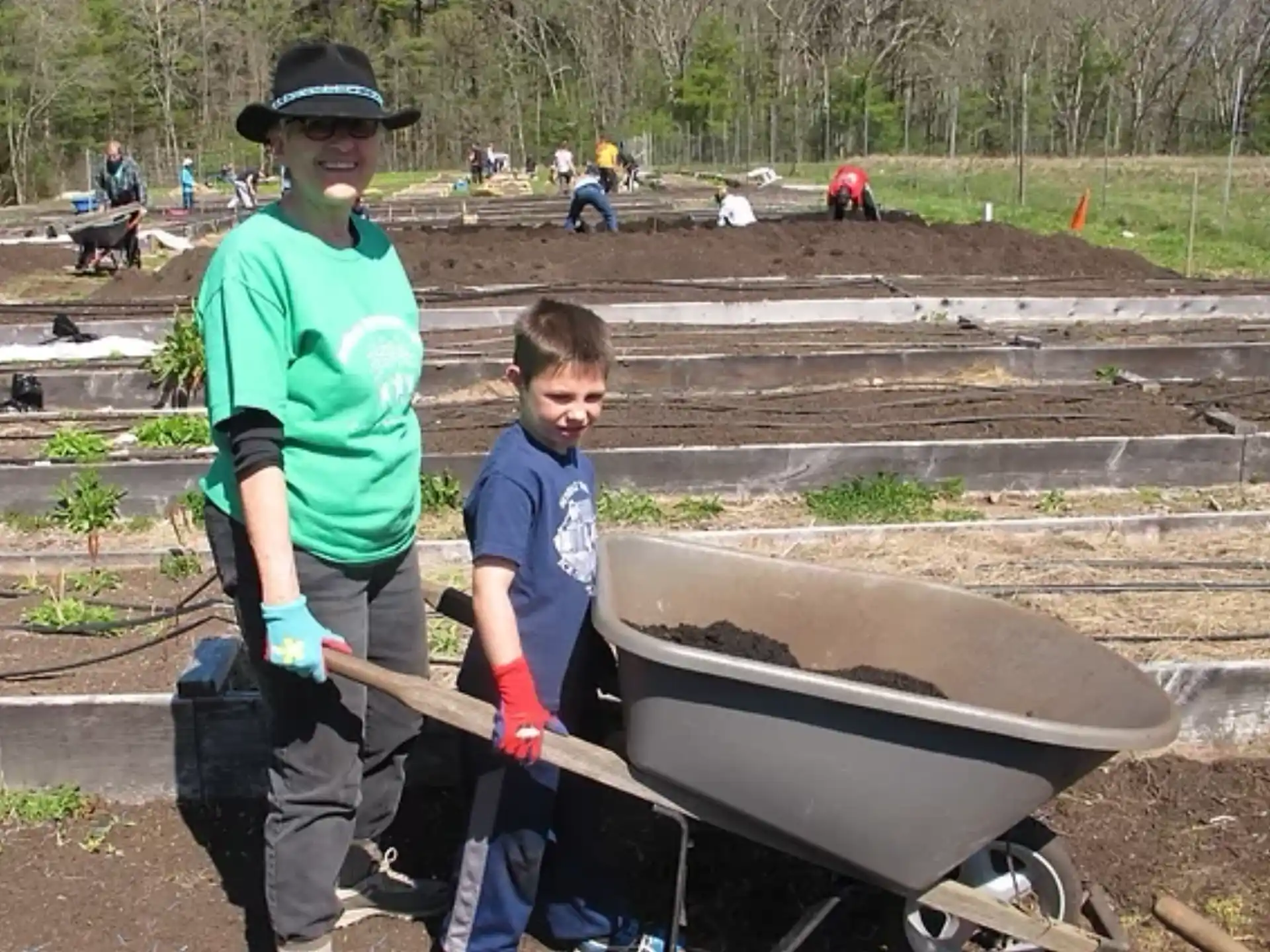 a person and a boy standing next to a wheelbarrow