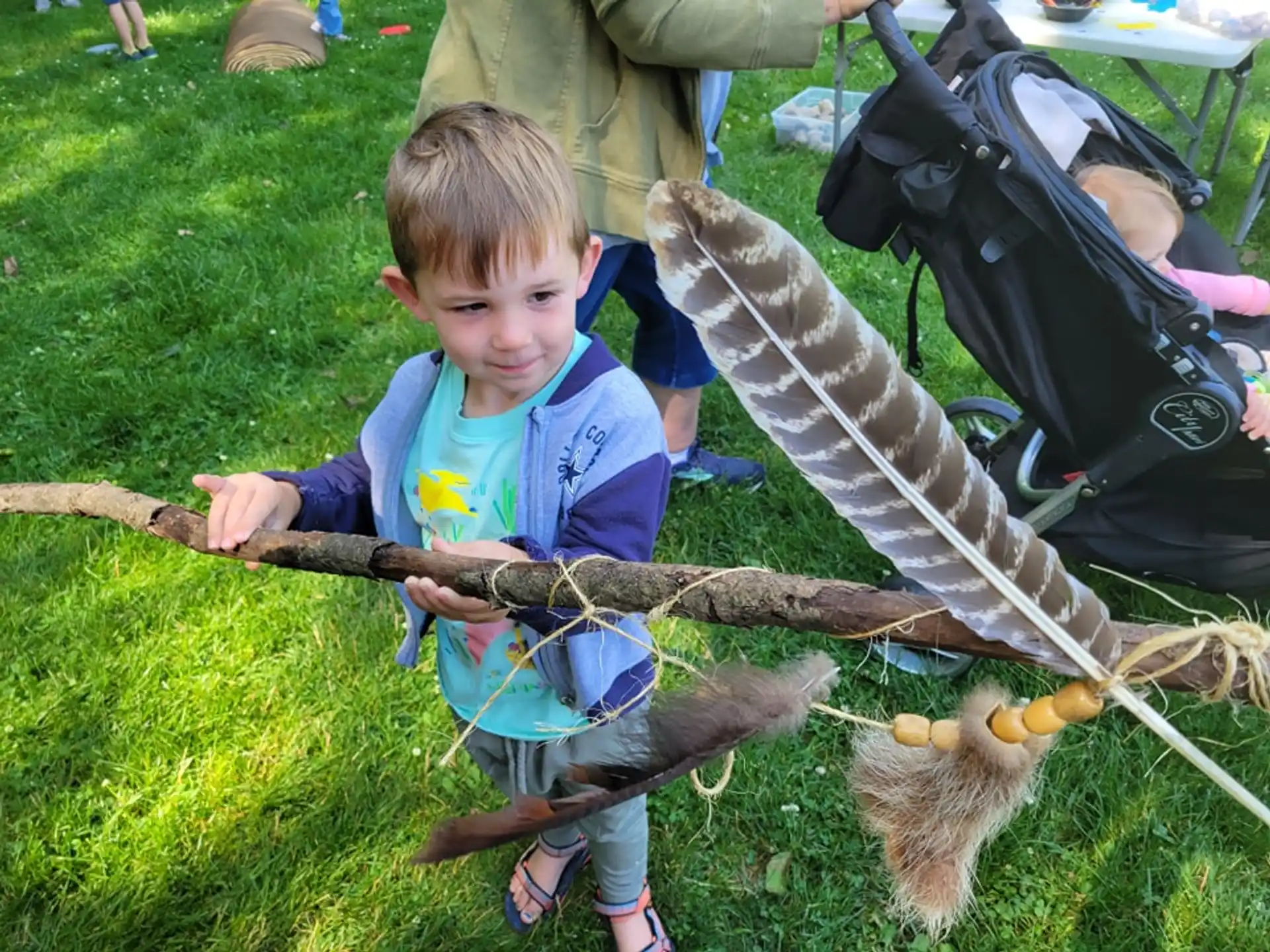 a boy holding a stick and a cat in a grassy area
