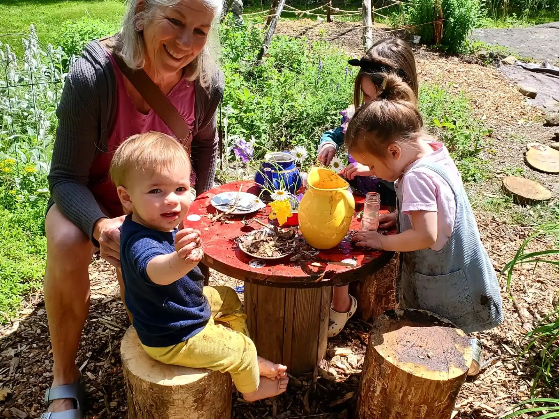 a person and several children sitting around a table outside