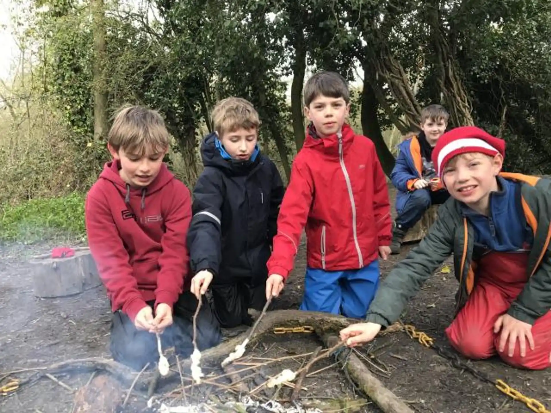a group of boys standing around a fire