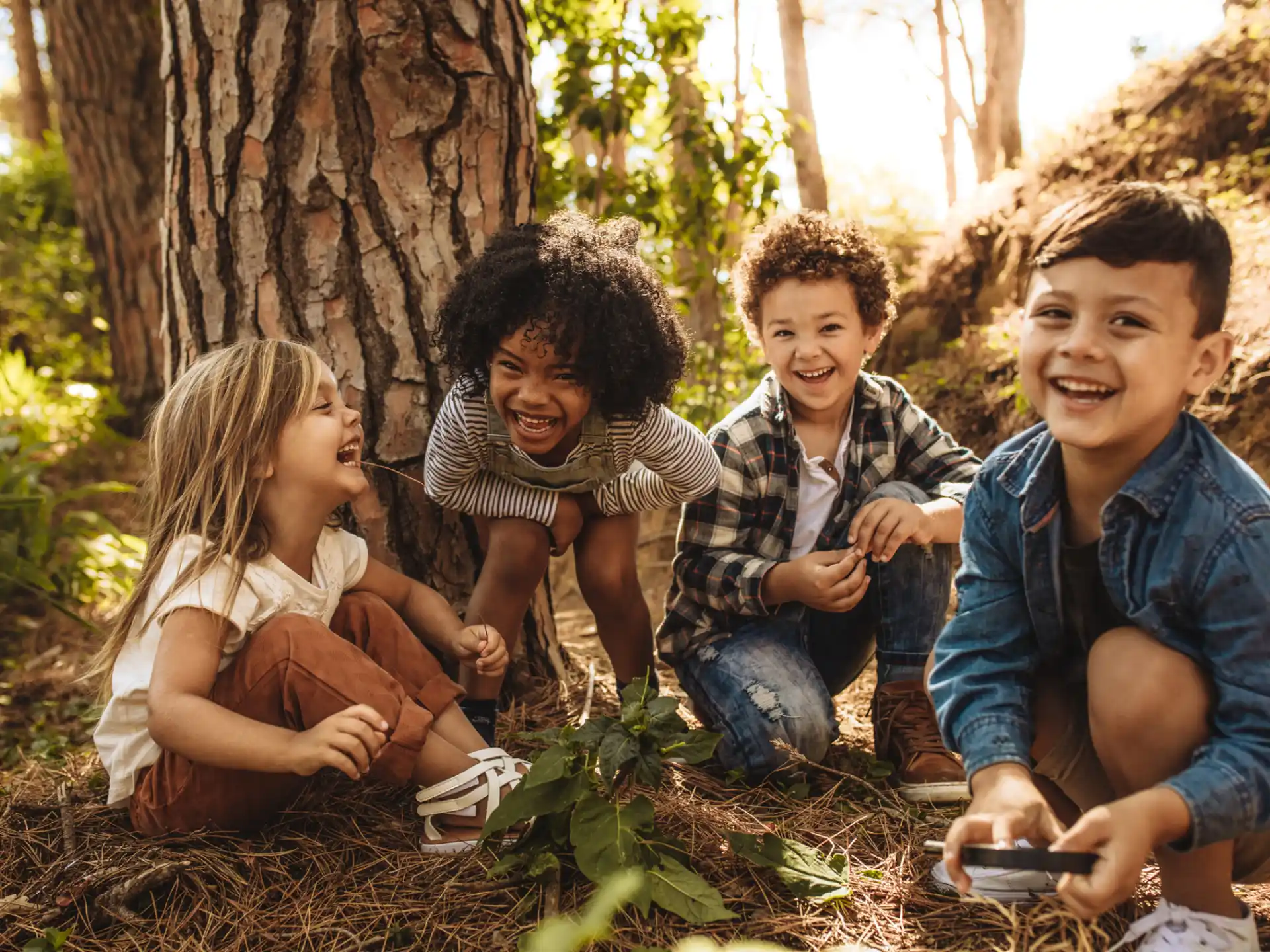a group of children sitting on the ground by a tree