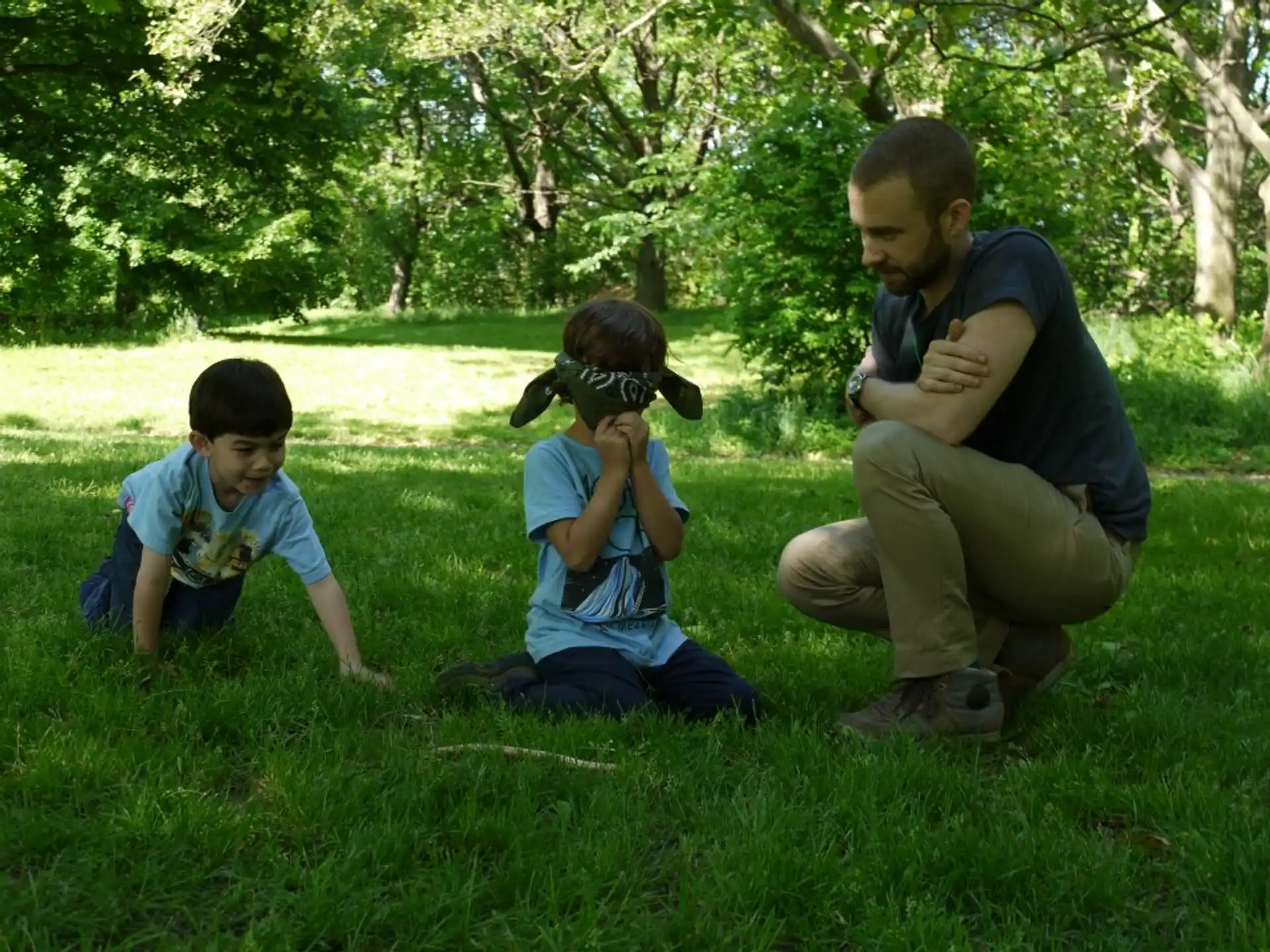 a person and two boys sitting in the grass with a camera