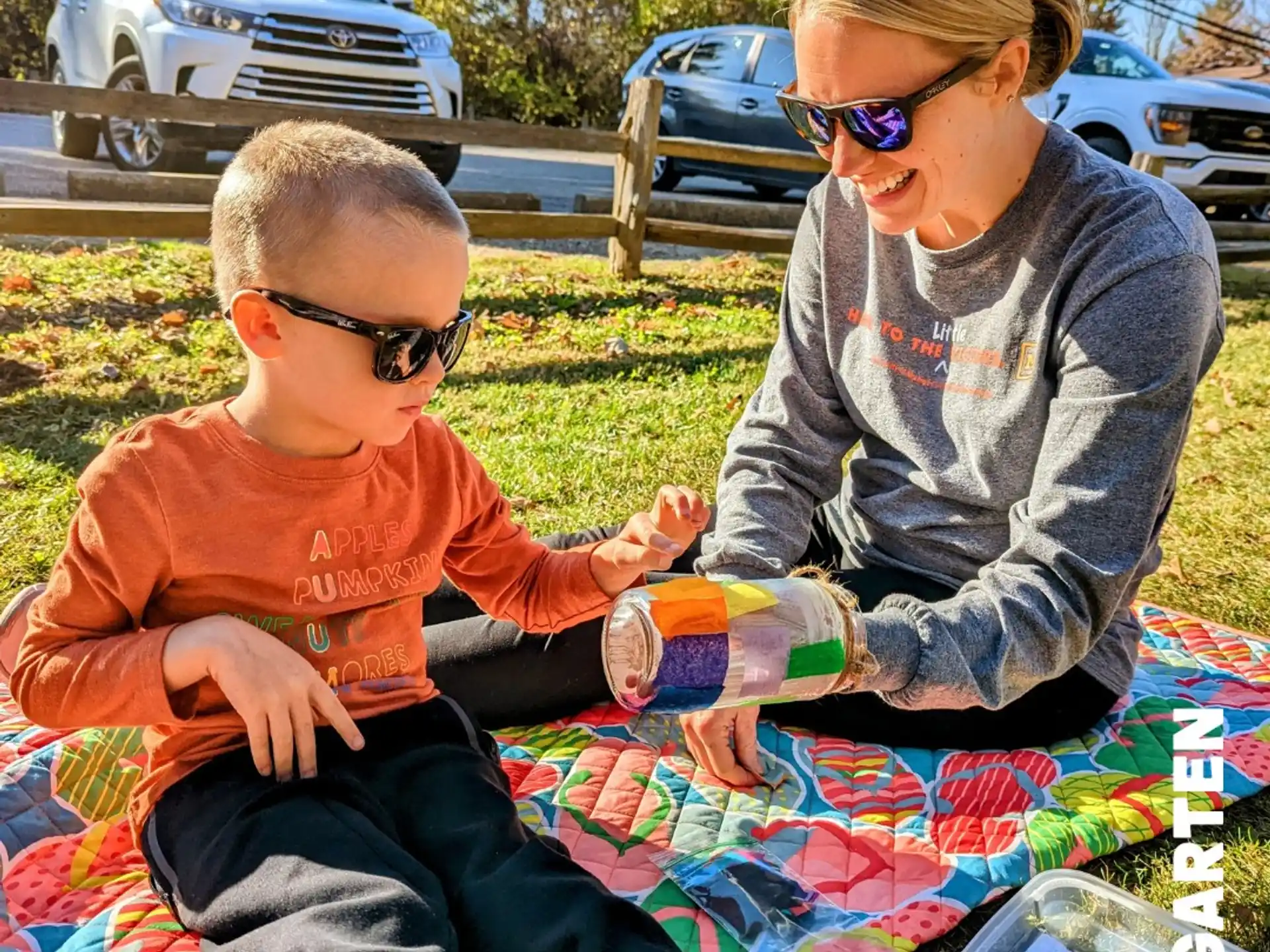a person and a boy sitting on a blanket outside