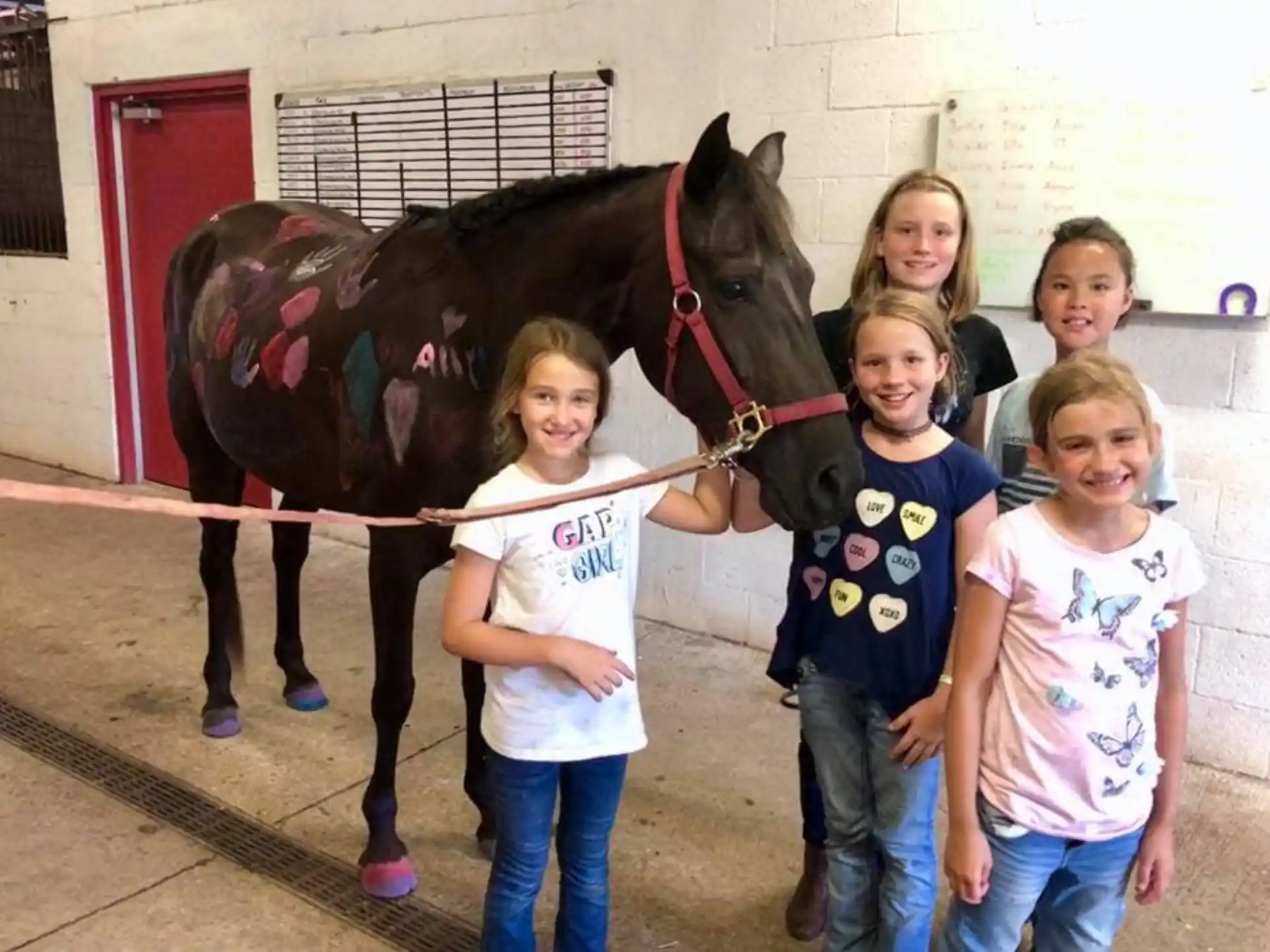 a group of children posing for a photo in front of a horse