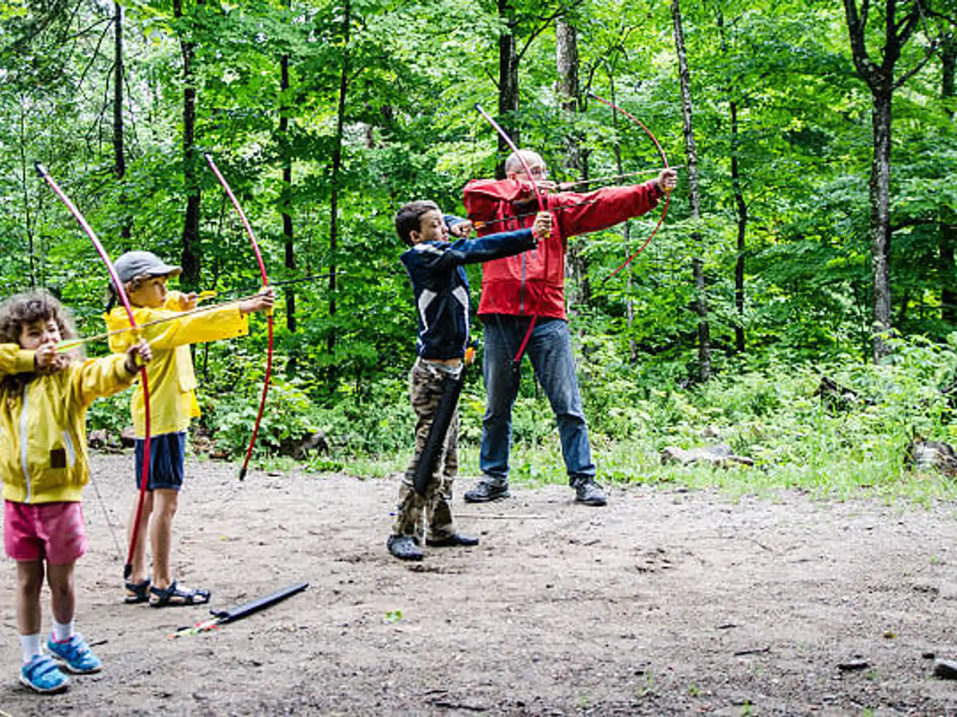 a group of people holding bows and arrows in the woods