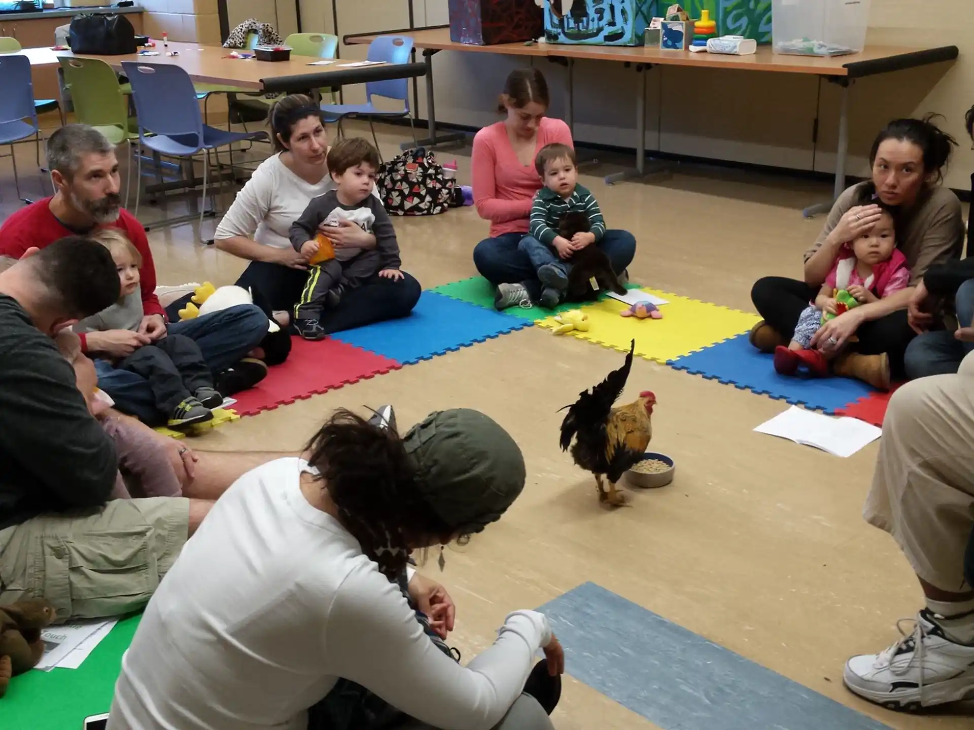 a group of people sitting on the floor with a chicken