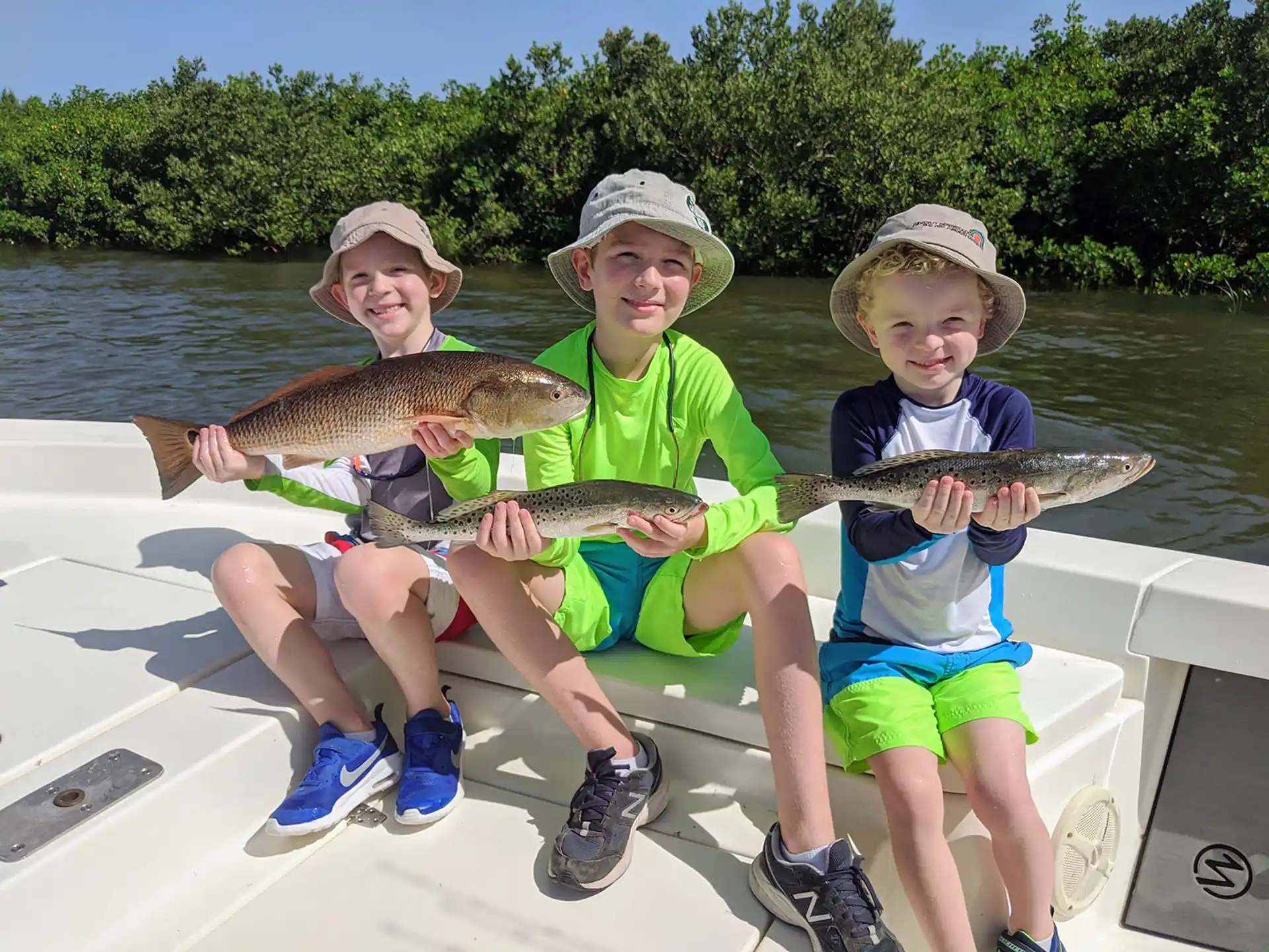 a group of kids holding fish on a boat