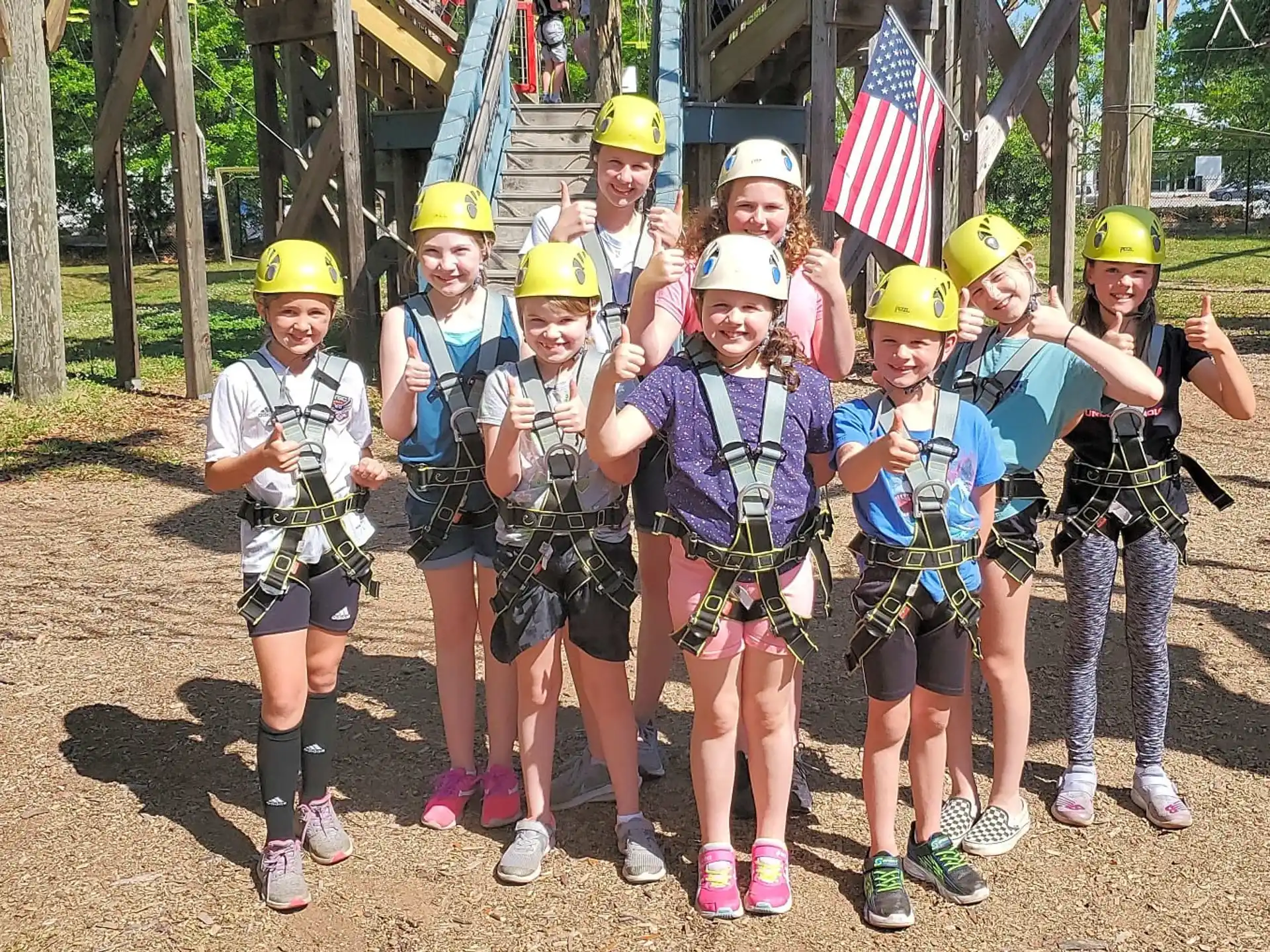 a group of kids wearing helmets and standing in front of a flag