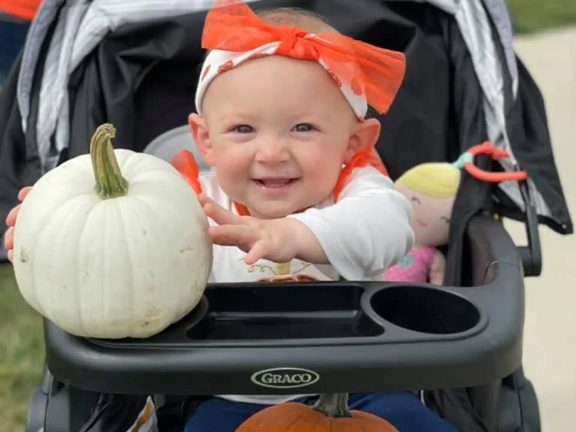 a baby in a stroller with pumpkins and a baby in it