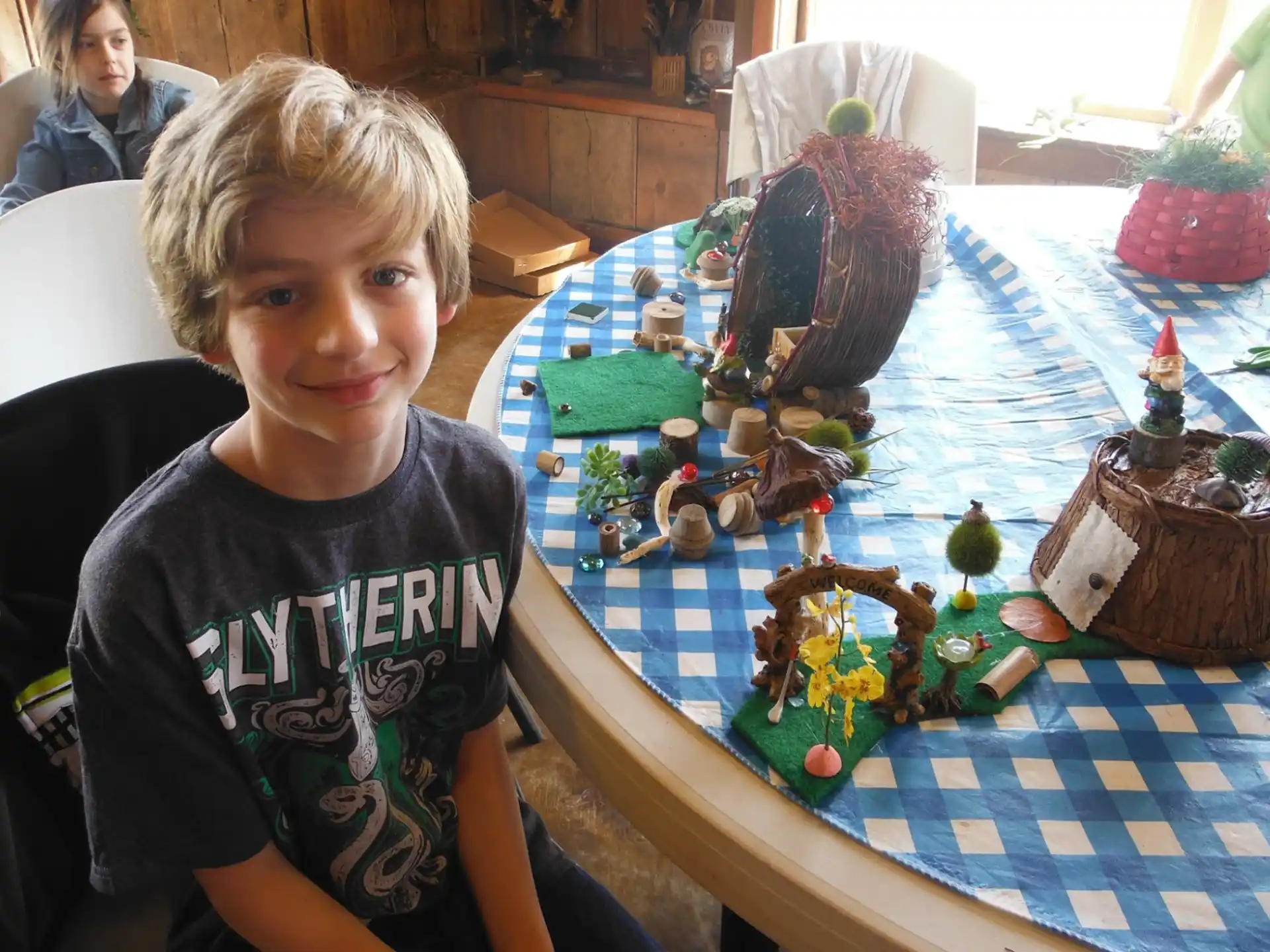 a boy sitting at a table with a toy train and a girl
