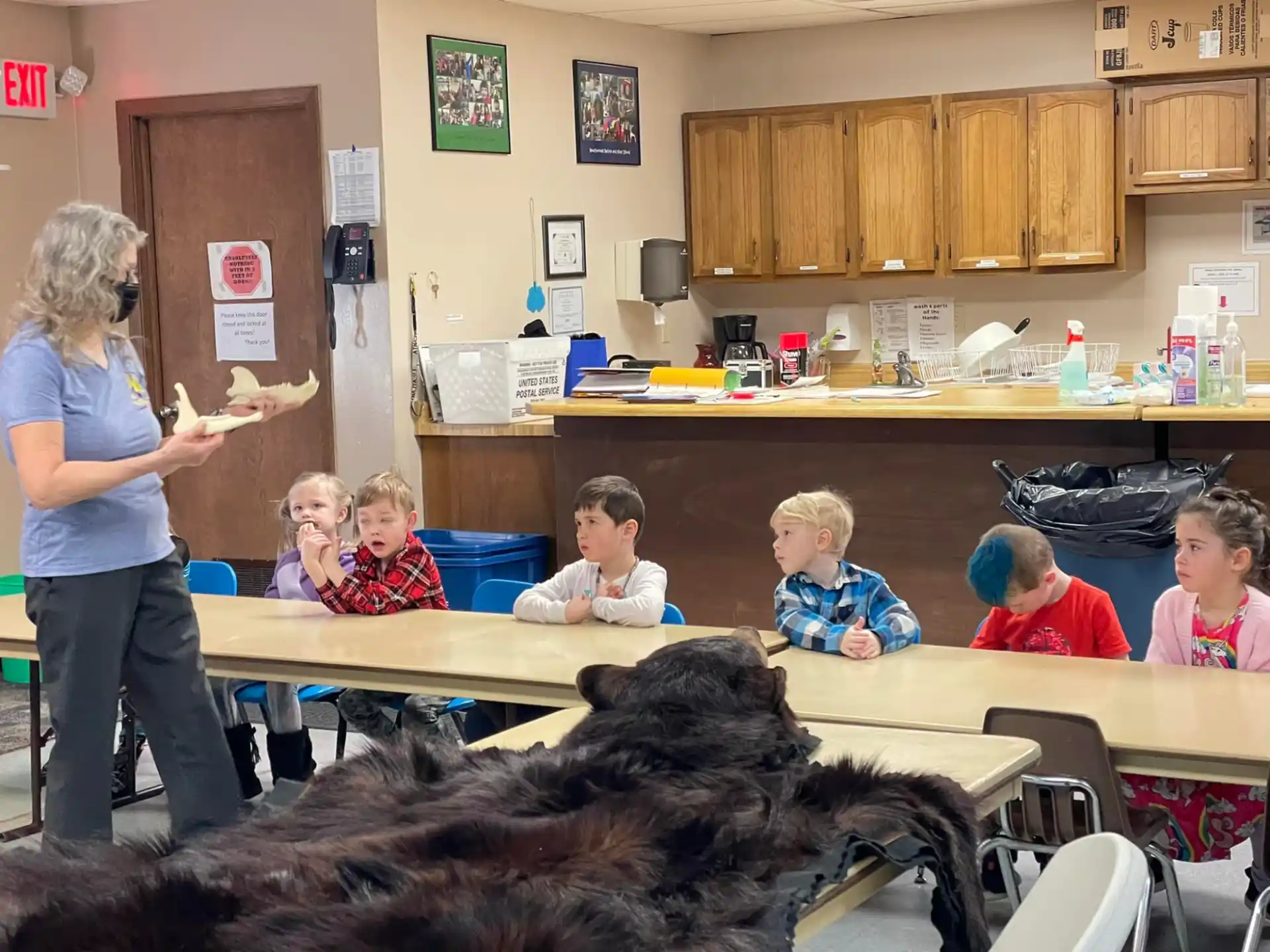 a person and a group of children sitting at a table