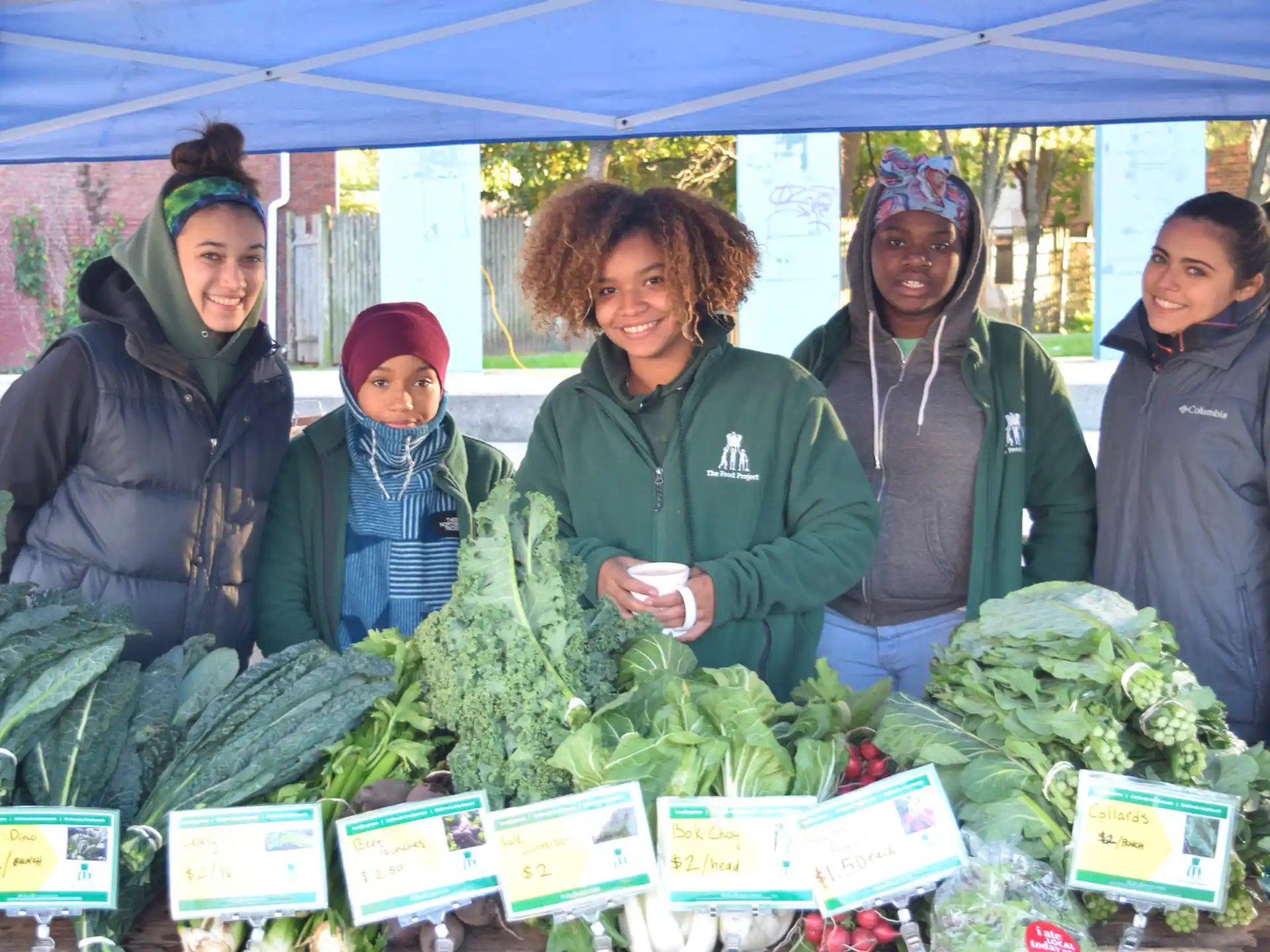 a group of women standing next to some vegetables