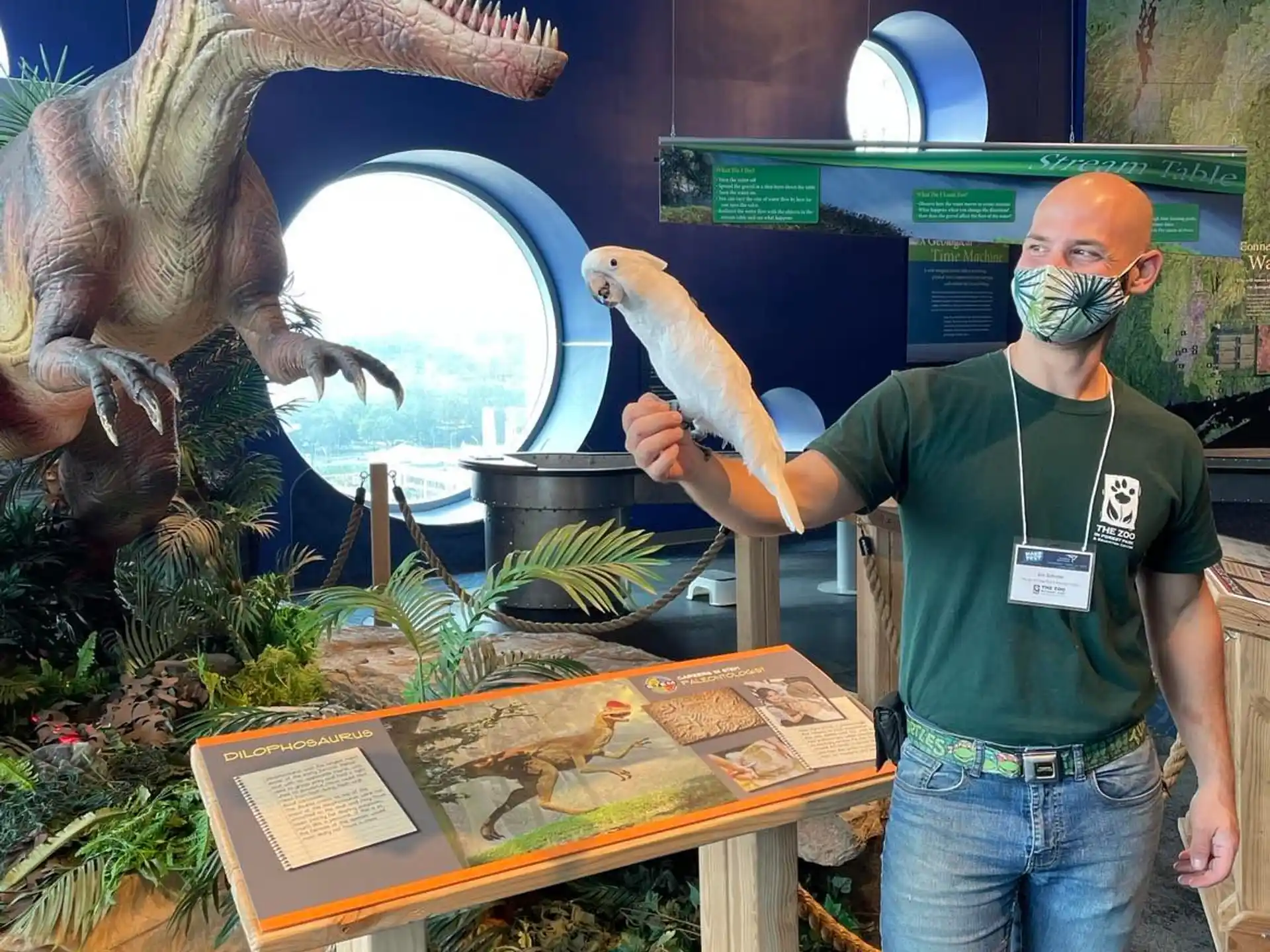 a man standing next to a dinosaur statue