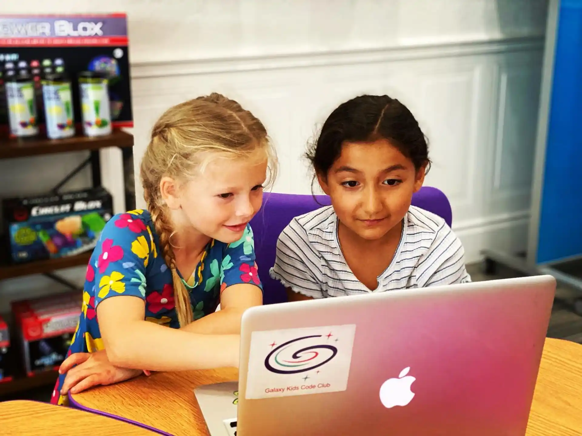 a couple of girls looking at a laptop